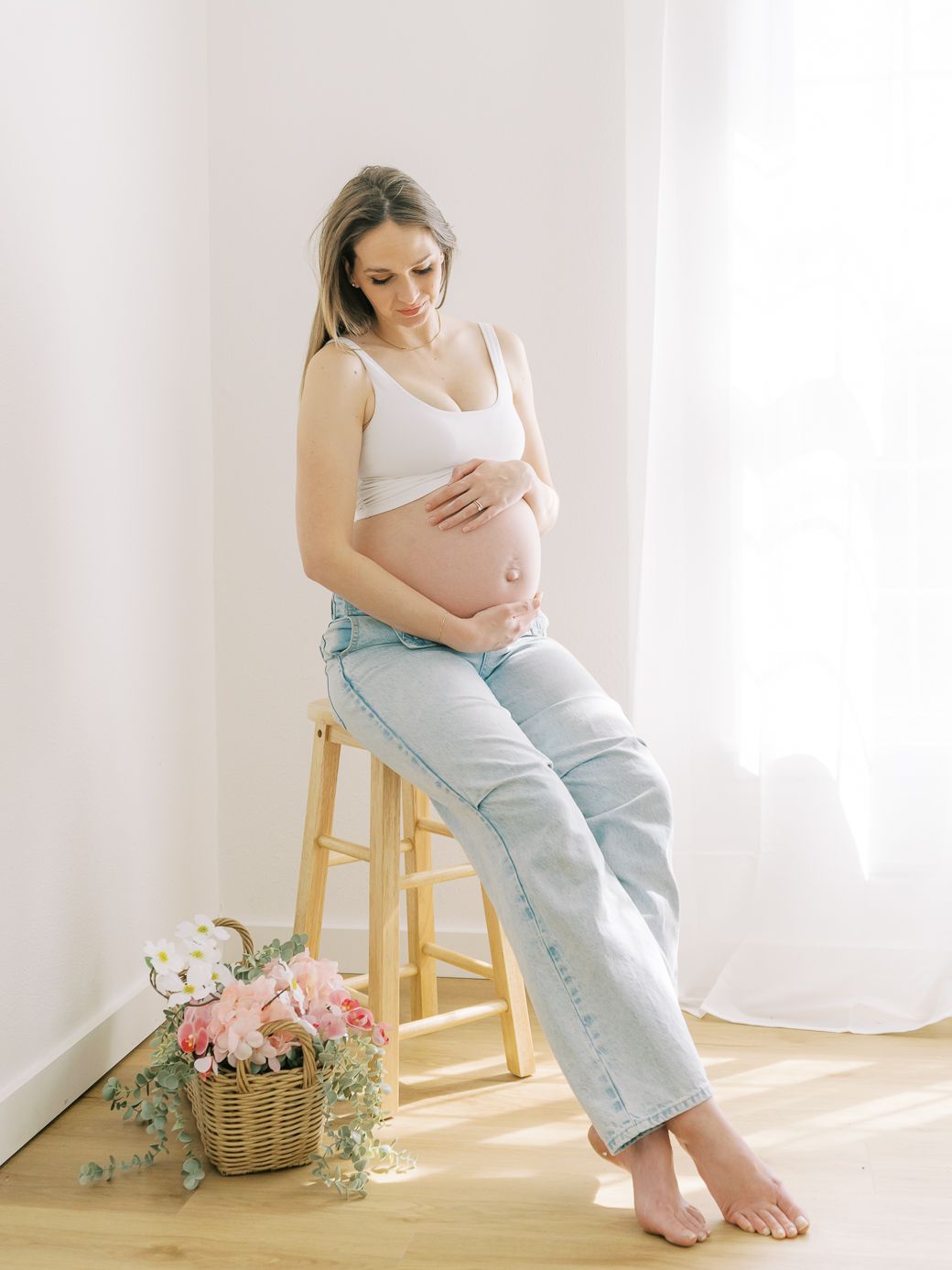 Soft and airy maternity portraits with vintage wooden stool and floral basket decor.