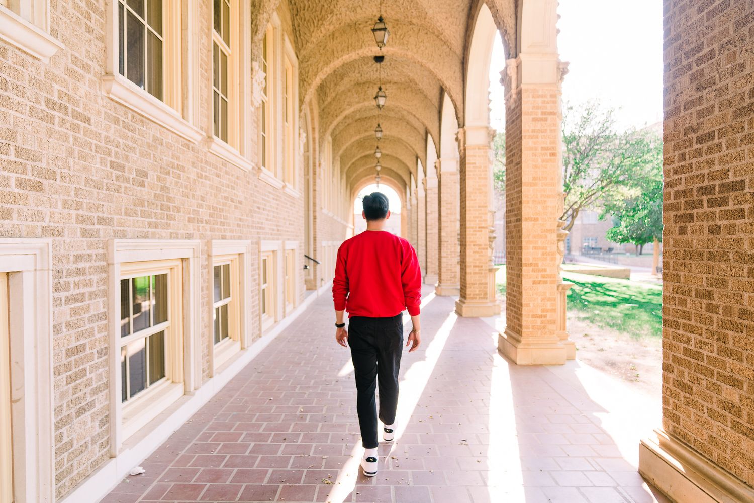 Long arched brick corridor with columns and windows creating architectural symmetry.