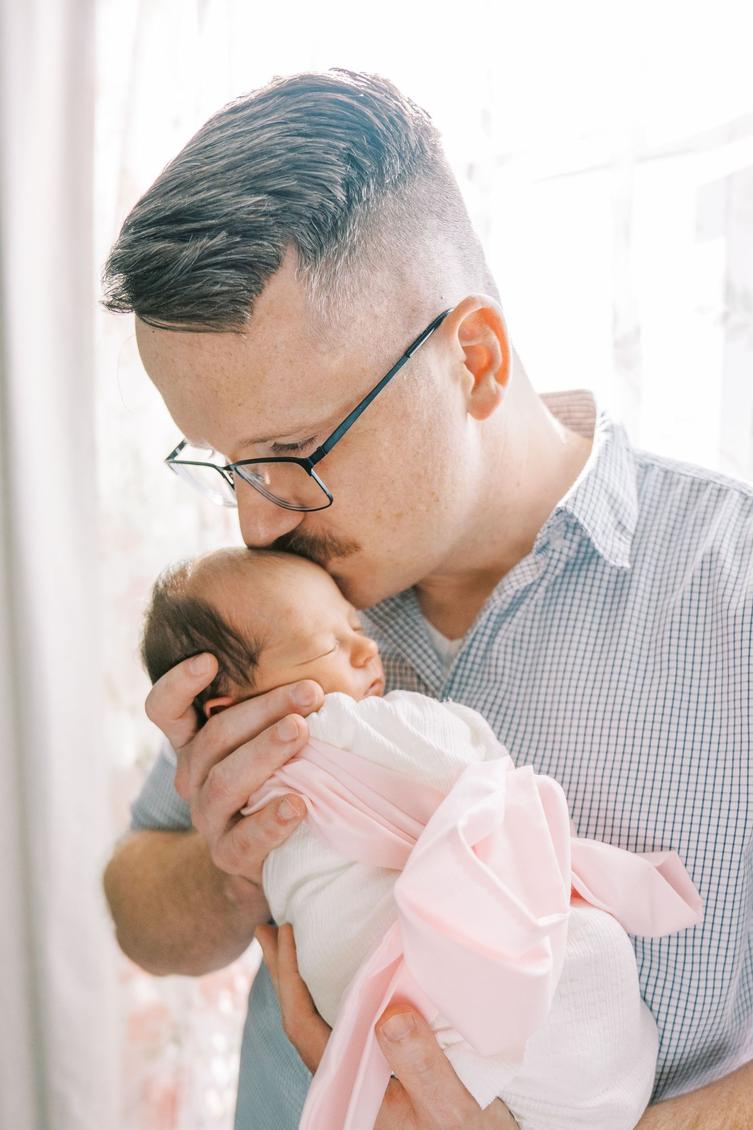 Series of intimate photos showing a parent bonding with a newborn baby wrapped in pink.