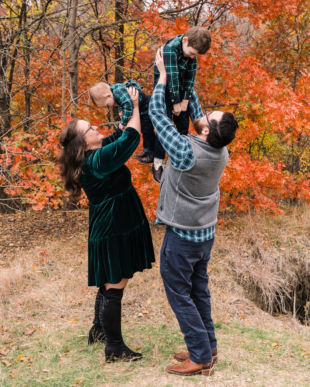 A couple dances playfully together against a backdrop of bright orange and red fall trees.