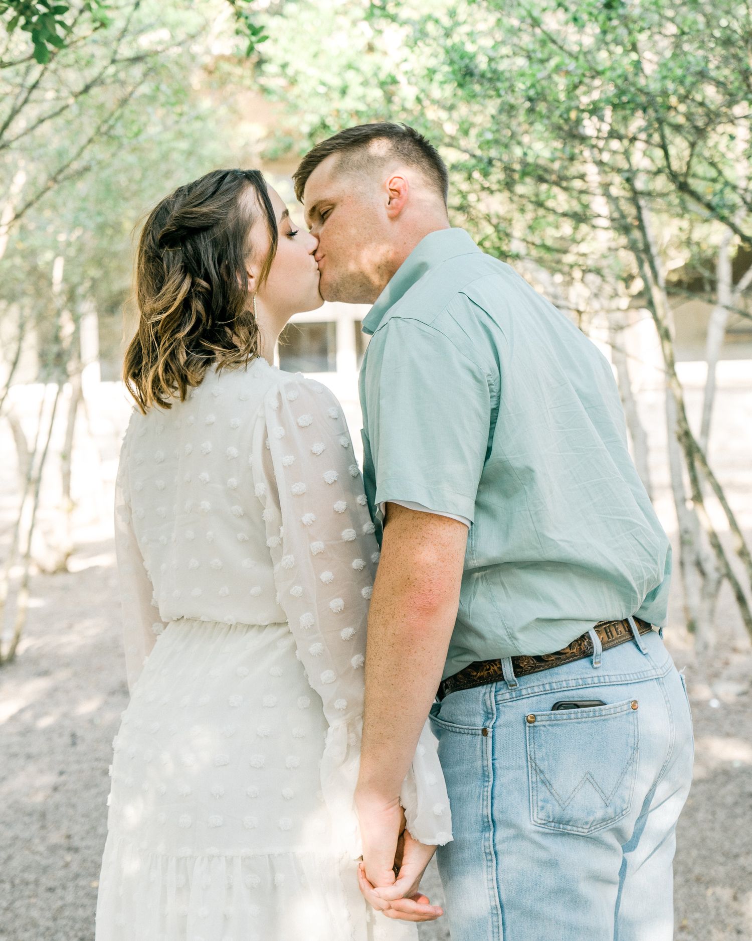 Romantic couple in casual attire sharing intimate moments in outdoor garden setting.