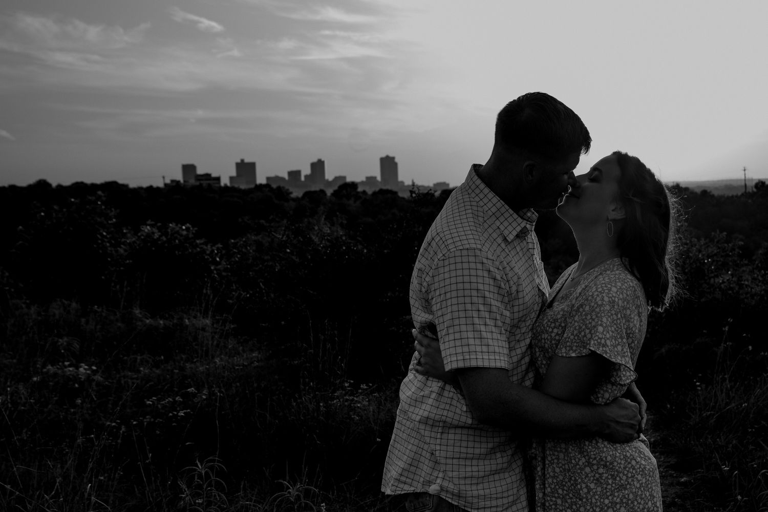 A silhouetted couple embraces against a dramatic city skyline at dusk.