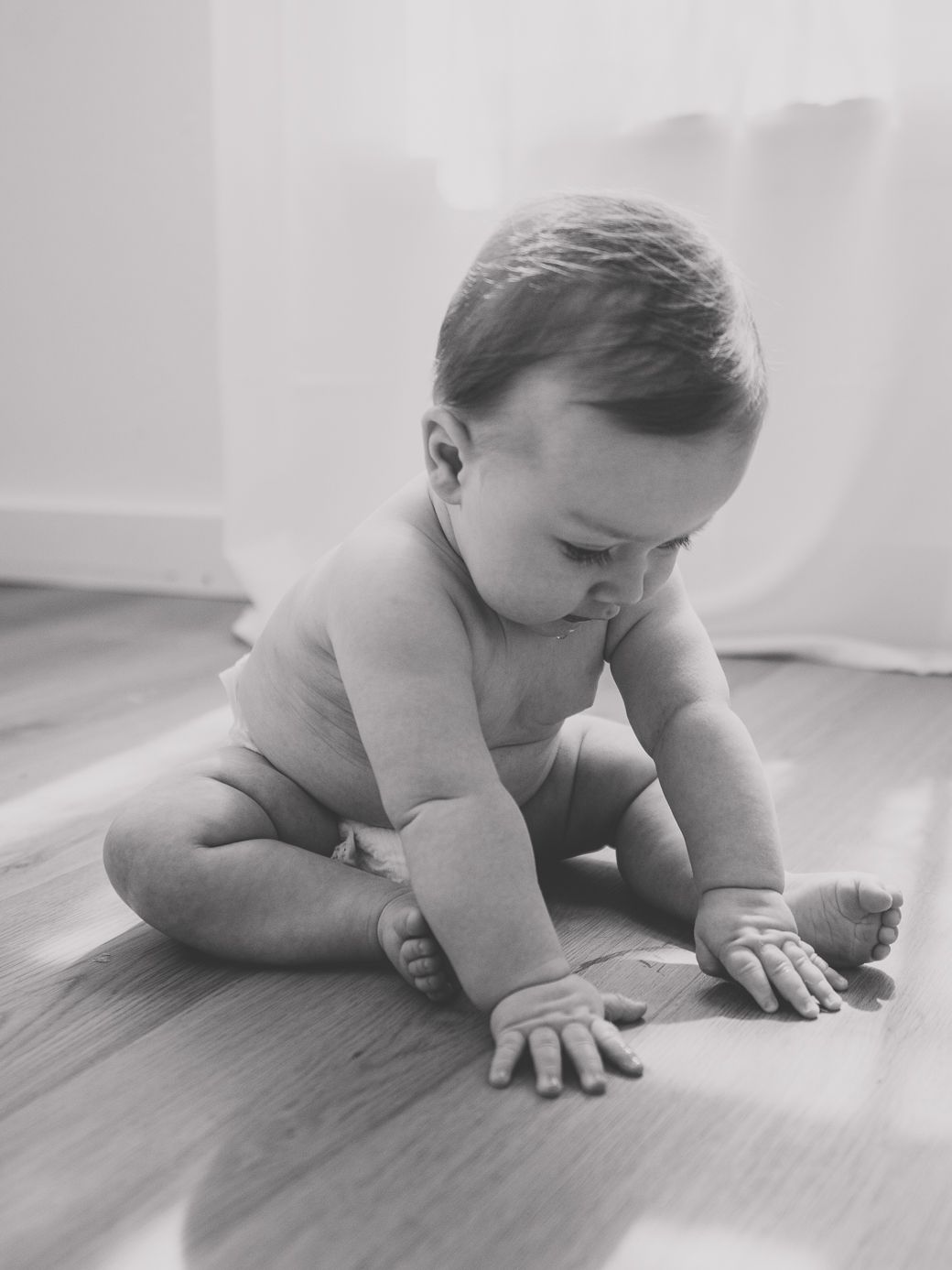Black and white photo series of a baby crawling and exploring on a light surface.