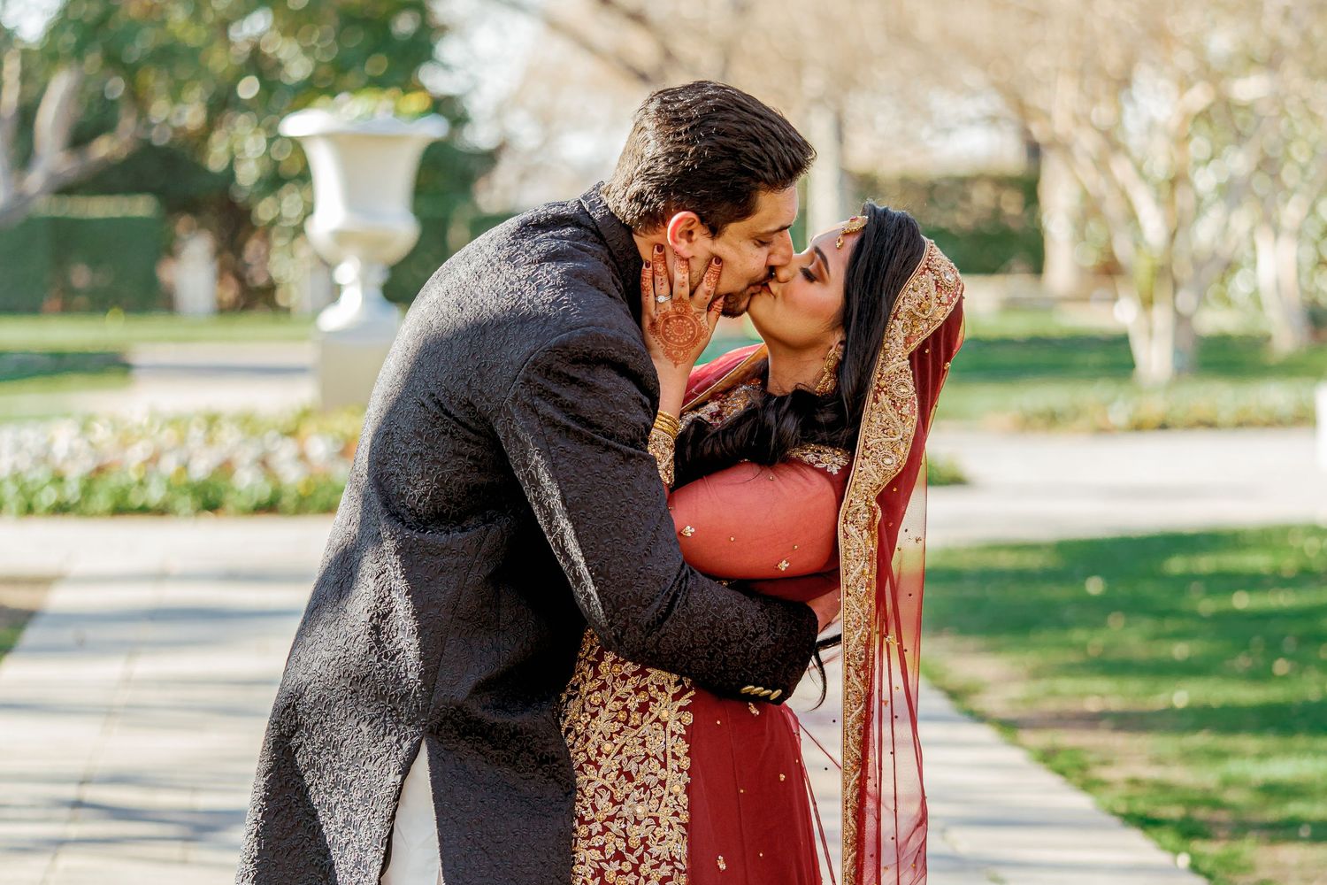 A couple embraces outdoors in a garden setting during a romantic photoshoot.