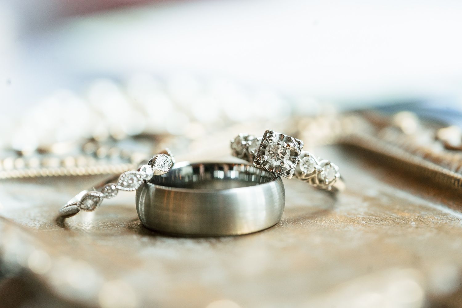 Wedding rings and jewelry arranged artistically in soft focus.