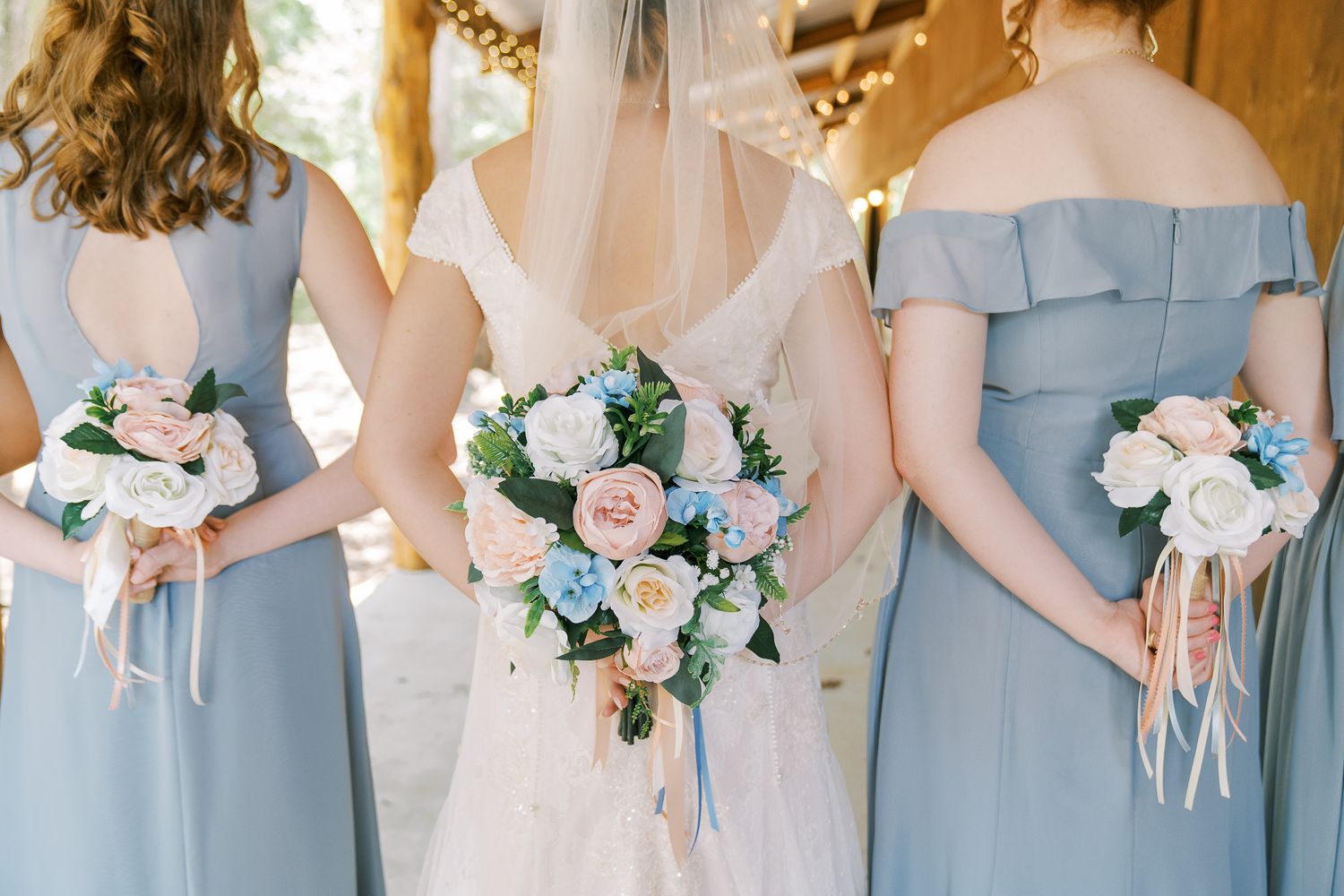 Bridesmaids in light blue dresses hold white and blue floral bouquets during an elegant wedding ceremony.
