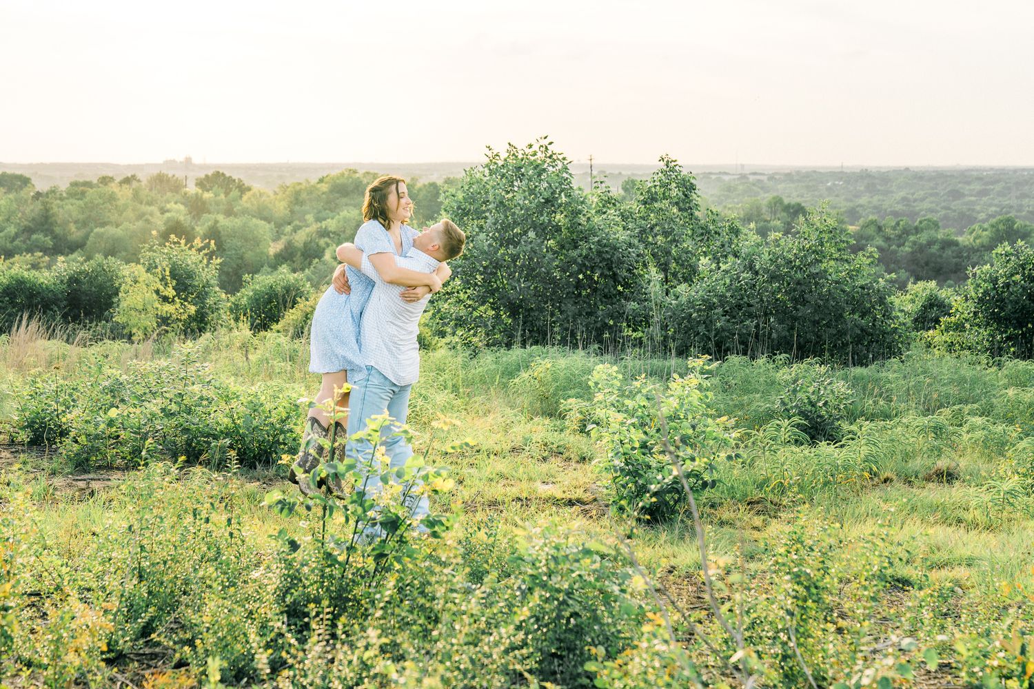 Panoramic view of a couple dancing in a vast wildflower meadow under blue skies.