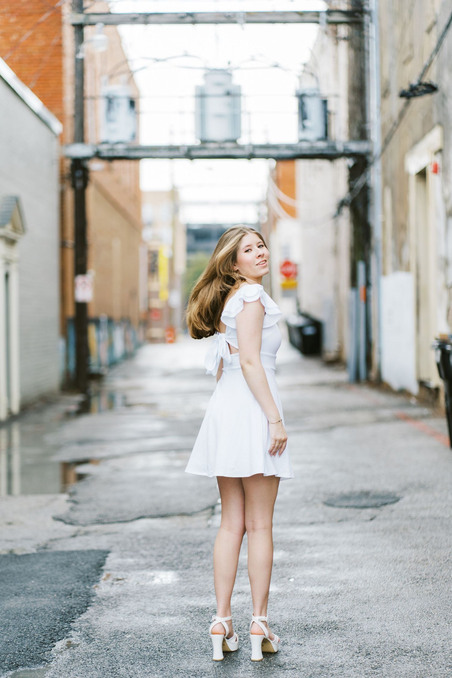 A series of five photos showing a person in a white dress walking down a charming cobblestone alley.
