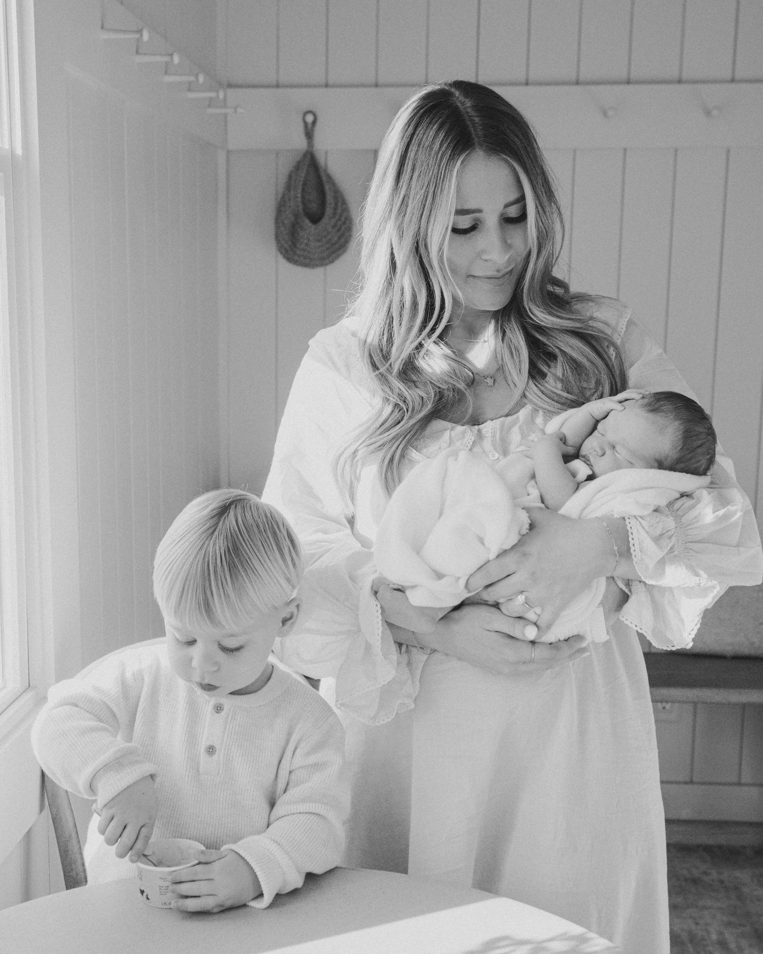 Family sharing tender moments in white clothing against white paneled walls.