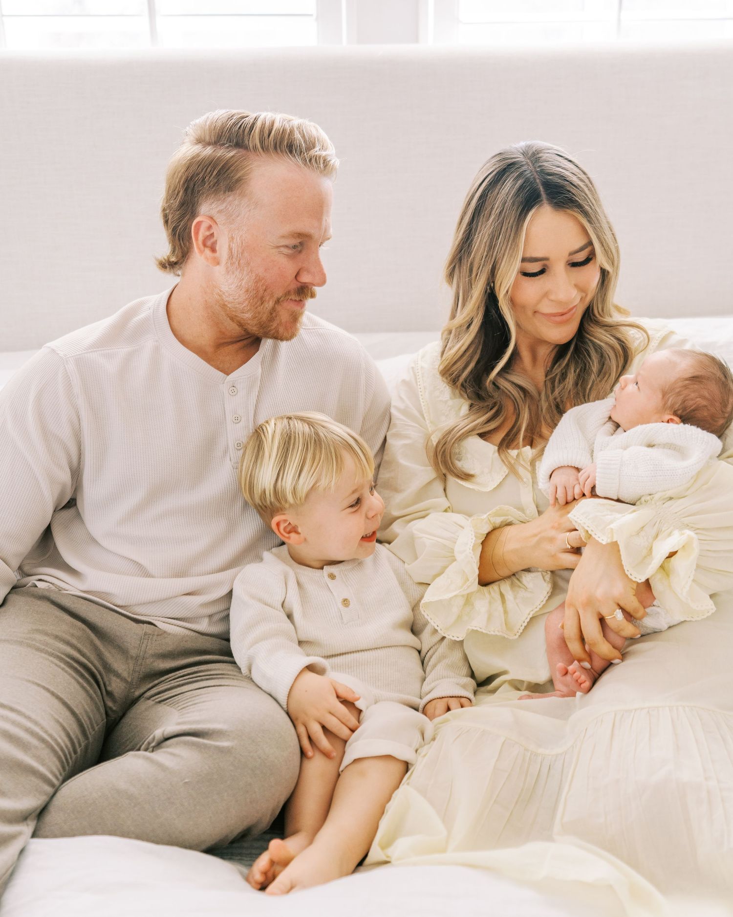 Family sitting together on white couch sharing intimate moment in bright room.