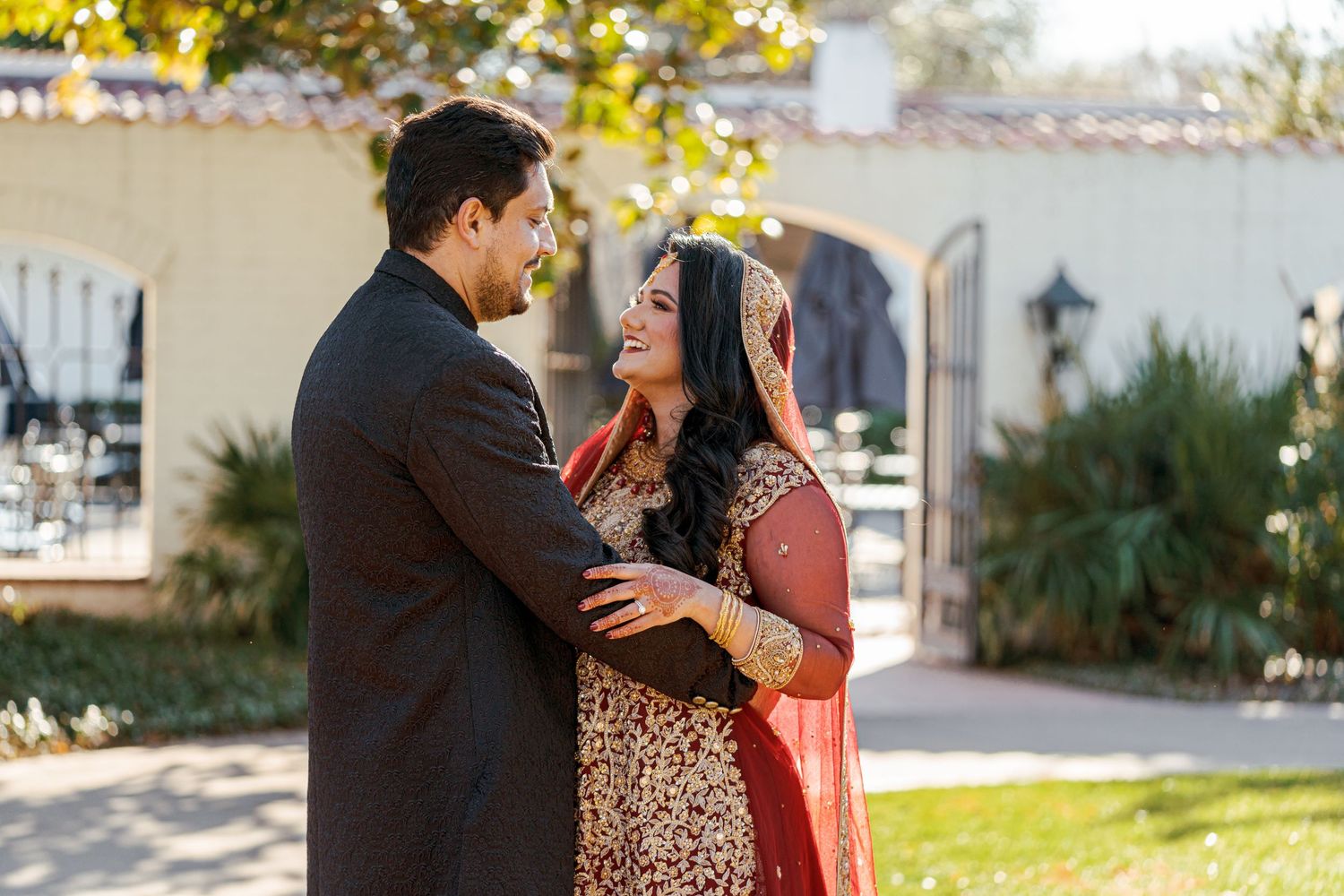 A couple embraces in front of a building exterior during a golden hour photography session.