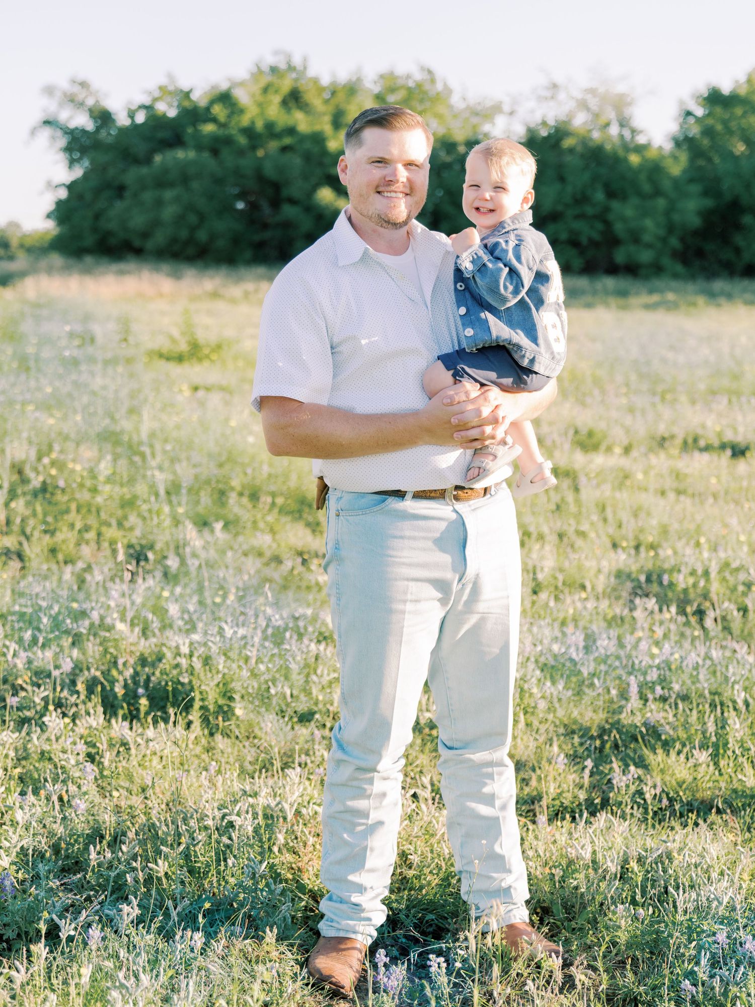 A family enjoying a sunny afternoon together in a wildflower meadow during golden hour.