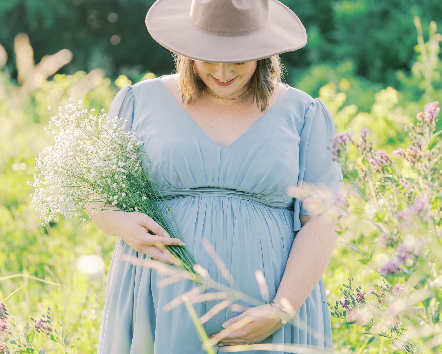Close-up shots of a maternity photo session featuring a blue dress and natural meadow setting.
