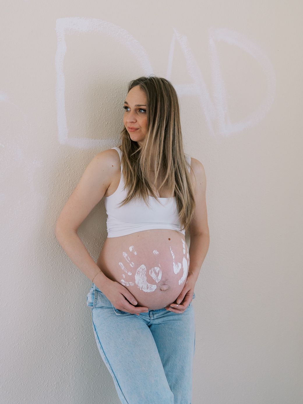 Artistic maternity photos showing painted handprints and hearts on pregnant belly.
