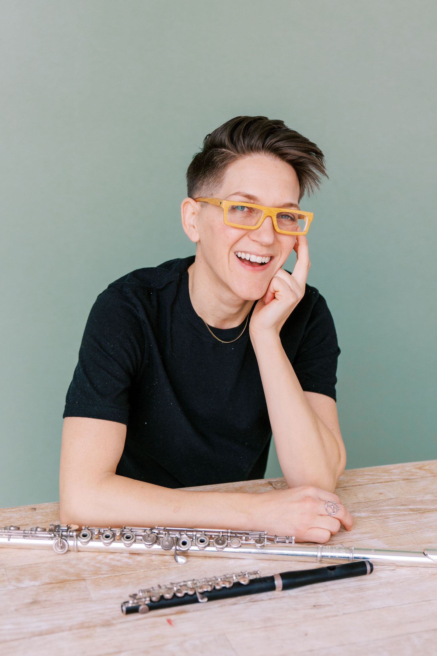 Series of candid shots showing a flutist in yellow glasses resting on a wooden table with their instrument.