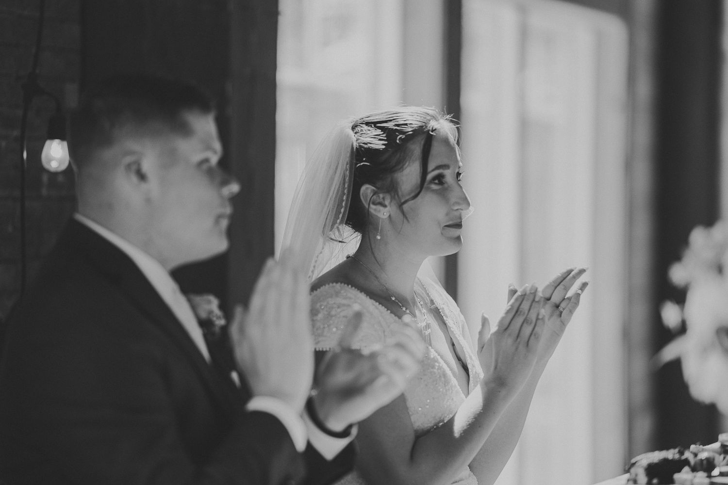Black and white photo of wedding guests reacting emotionally during a special moment.