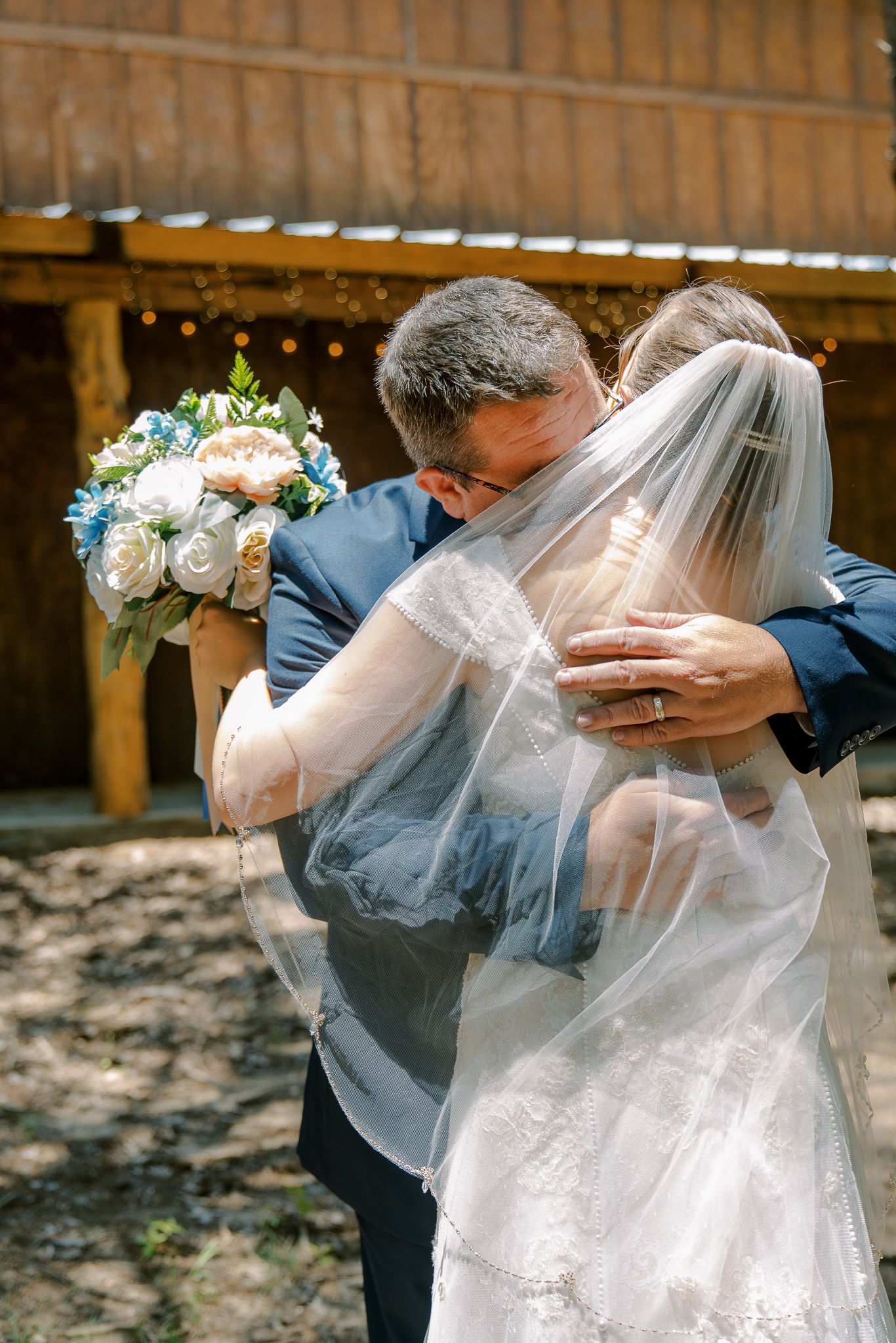 A romantic wedding moment captured in a rustic barn setting with soft natural light filtering through.