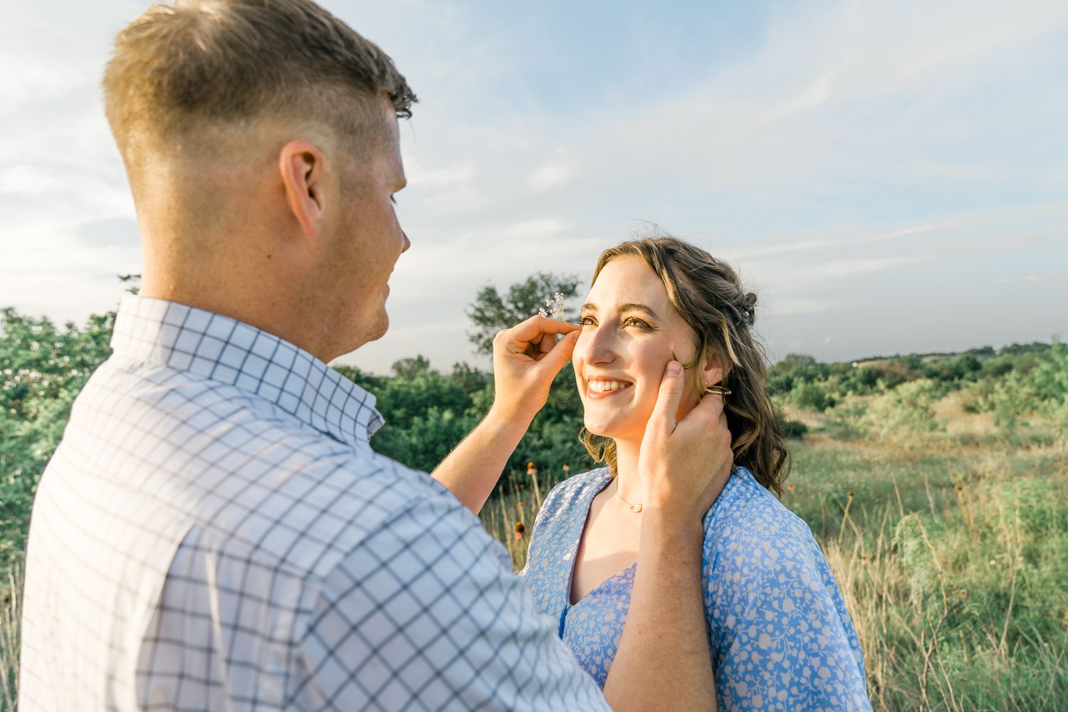 A couple shares intimate moments in a grassy field during golden hour.