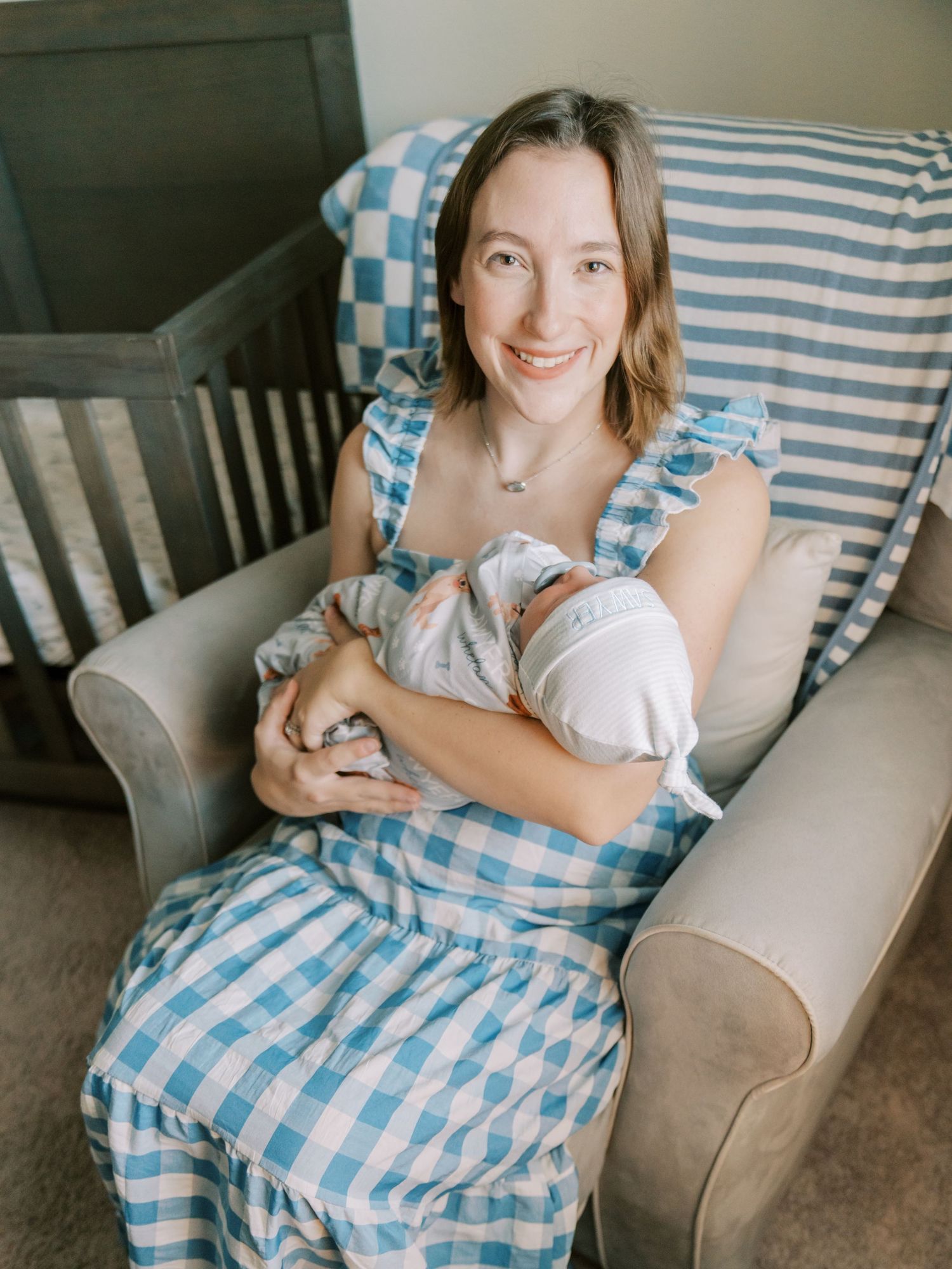 Person relaxing on a gray couch with blue and white checkered blanket in a cozy living room setting.