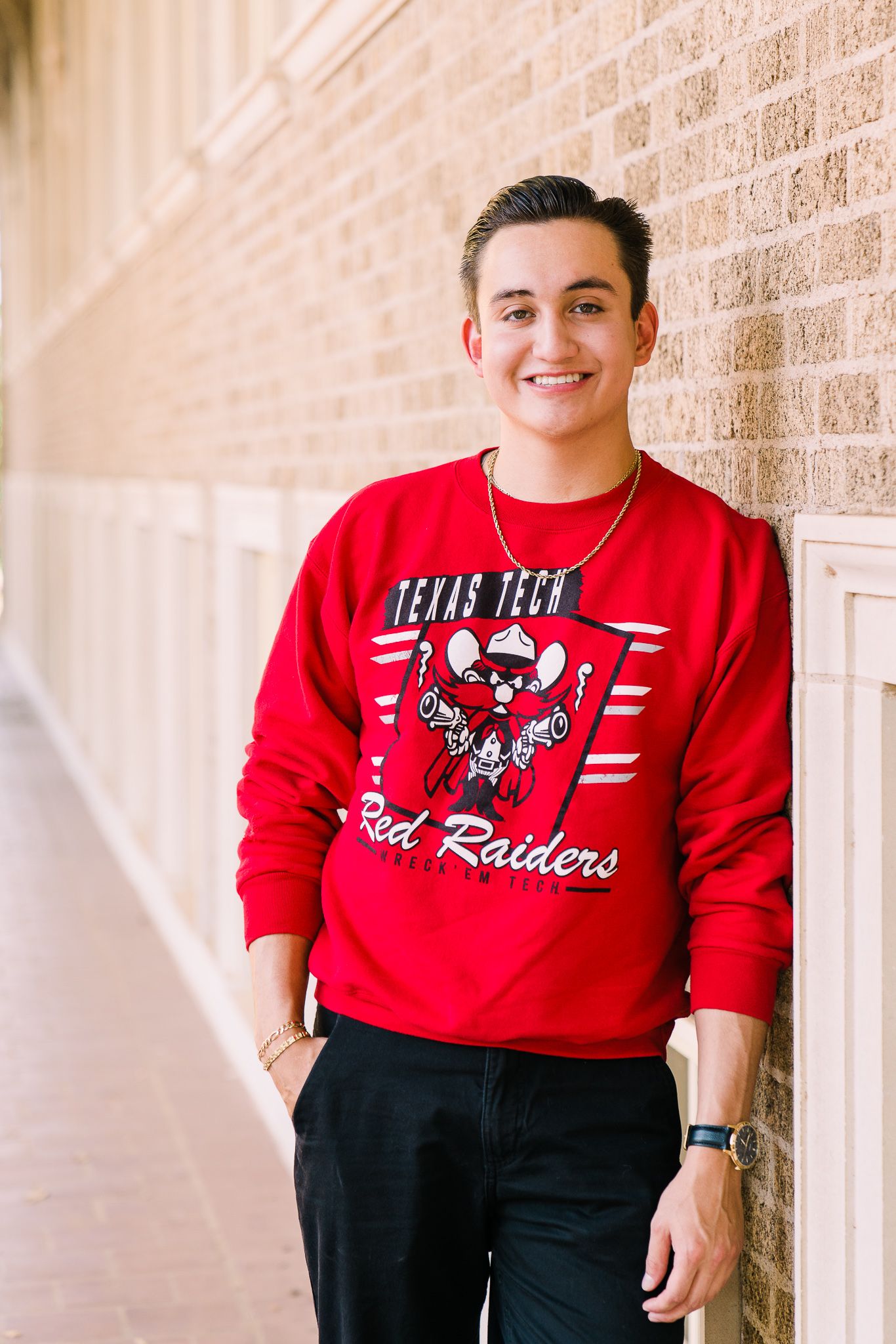Person wearing a red Raiders sweatshirt and black pants poses against a brick wall in multiple casual stances.
