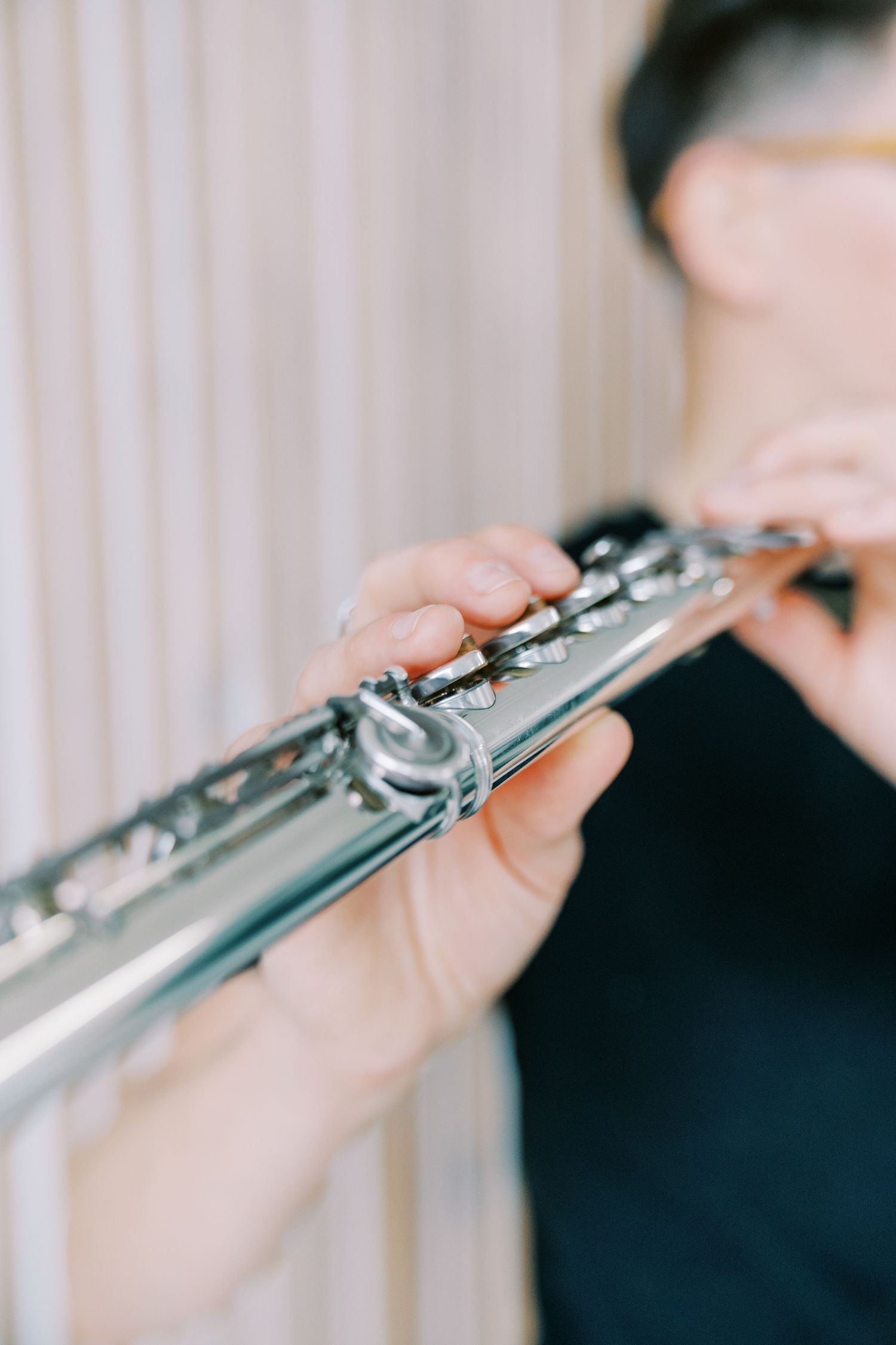 Close-up shot of hands playing a silver flute with delicate finger placement on the keys.
