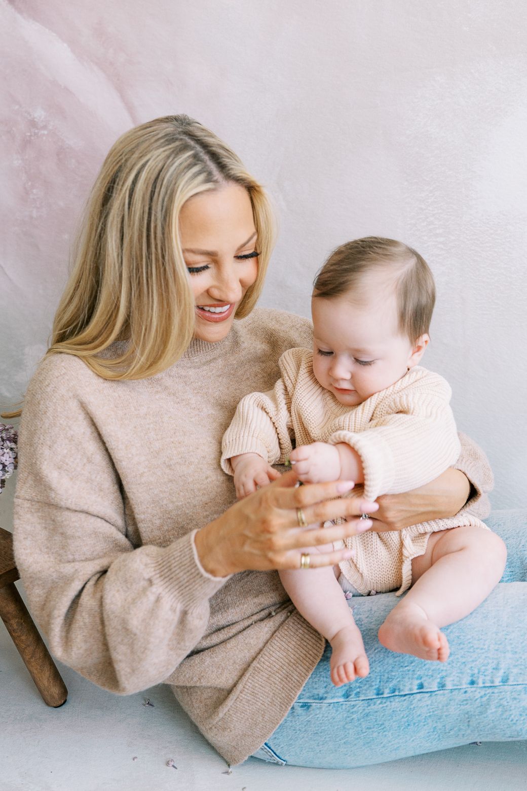A tender moment of parent and baby playing together on a light blue cushion in a series of candid lifestyle photos.