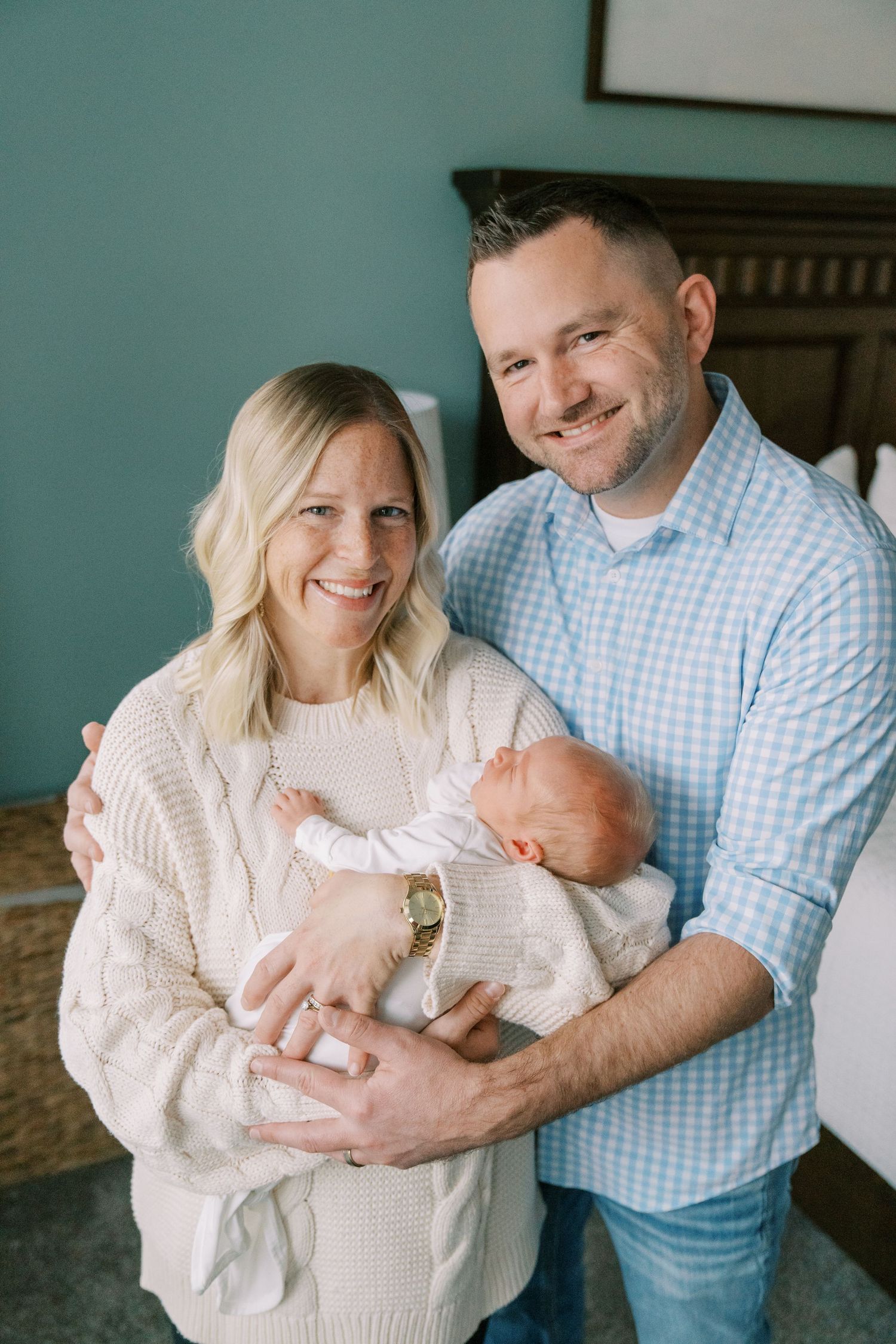 Family cuddles with newborn baby while wearing coordinating blue and cream outfits.