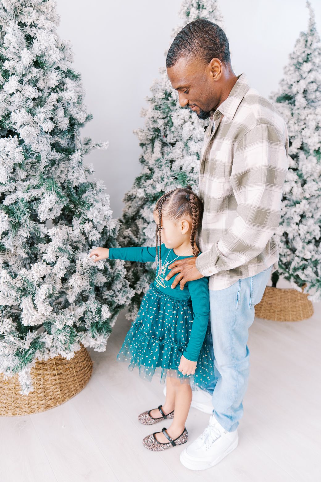 Candid family moments captured during a holiday photoshoot with decorated Christmas trees.