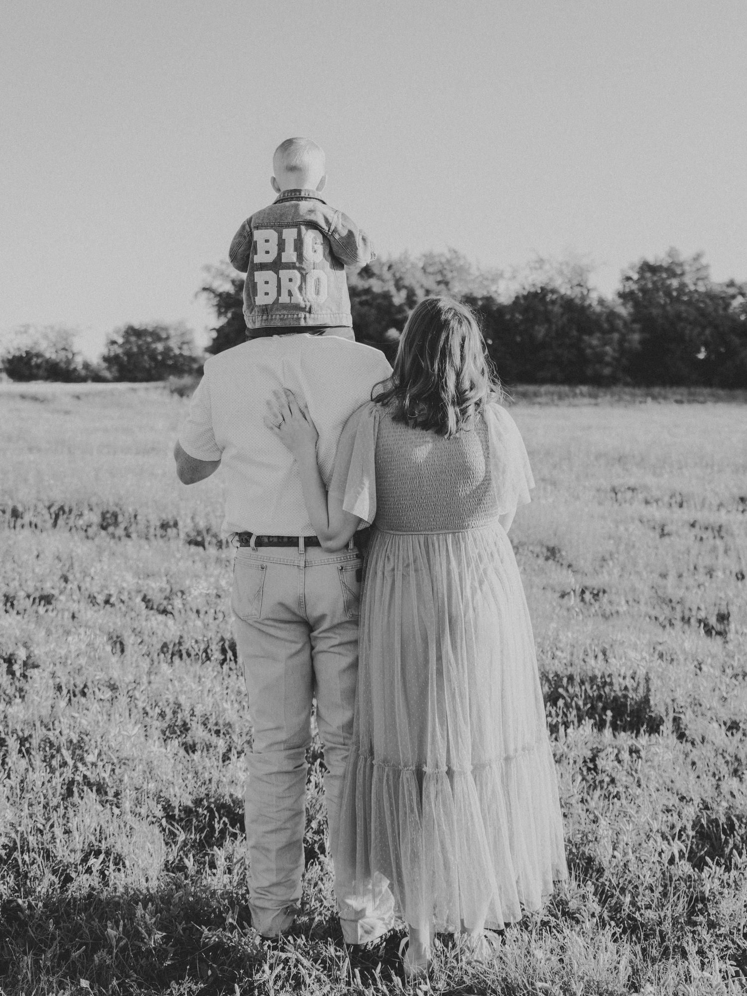 Black and white photo of a couple standing together in a wildflower field at sunset.