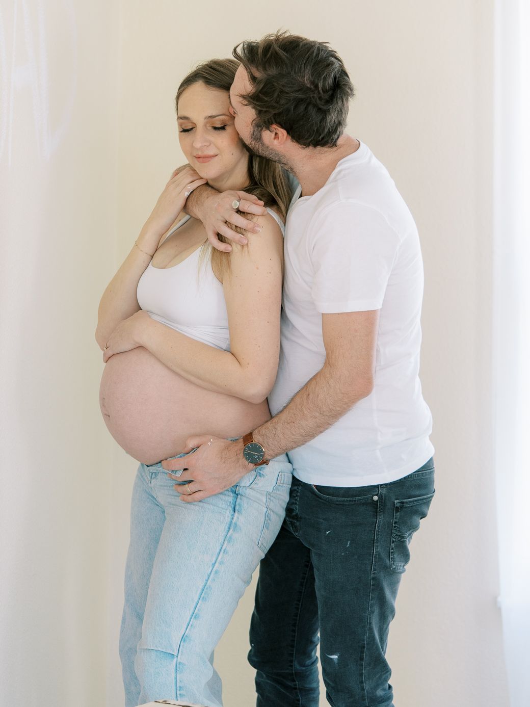Tender moment between expecting couple during maternity photoshoot.
