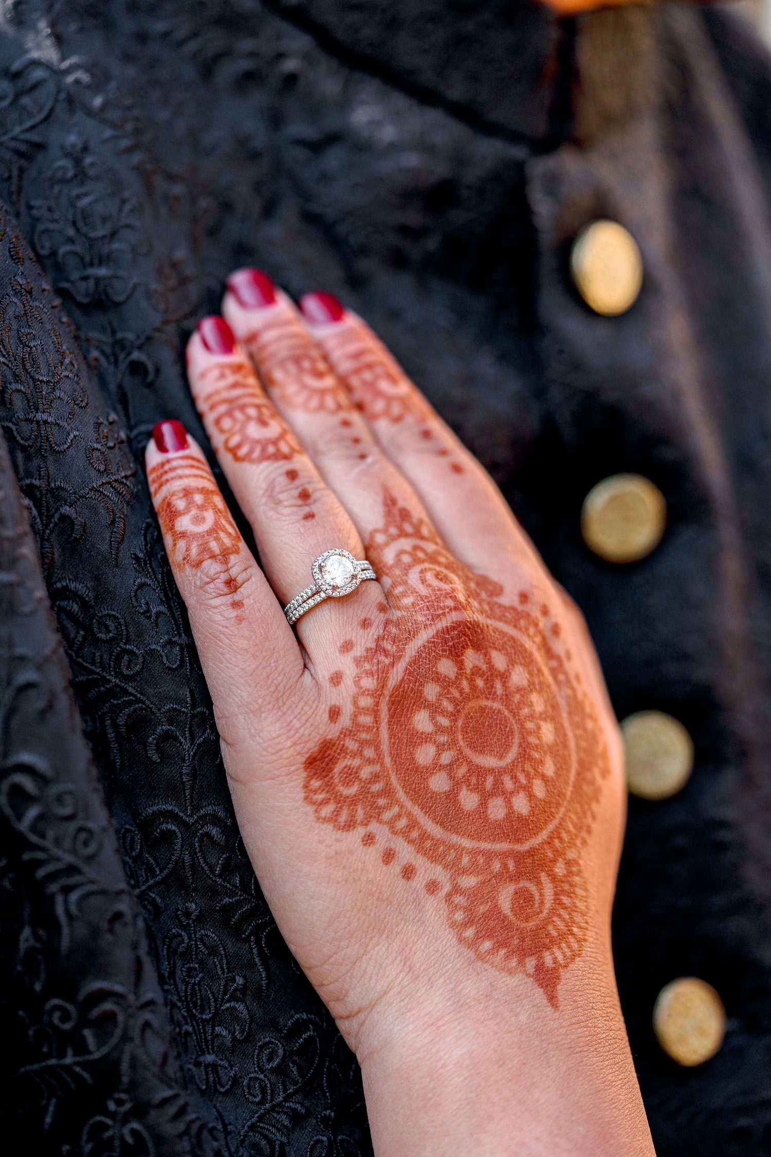 Close-up sequence showing intricate henna design and engagement ring on a hand against a dark background.