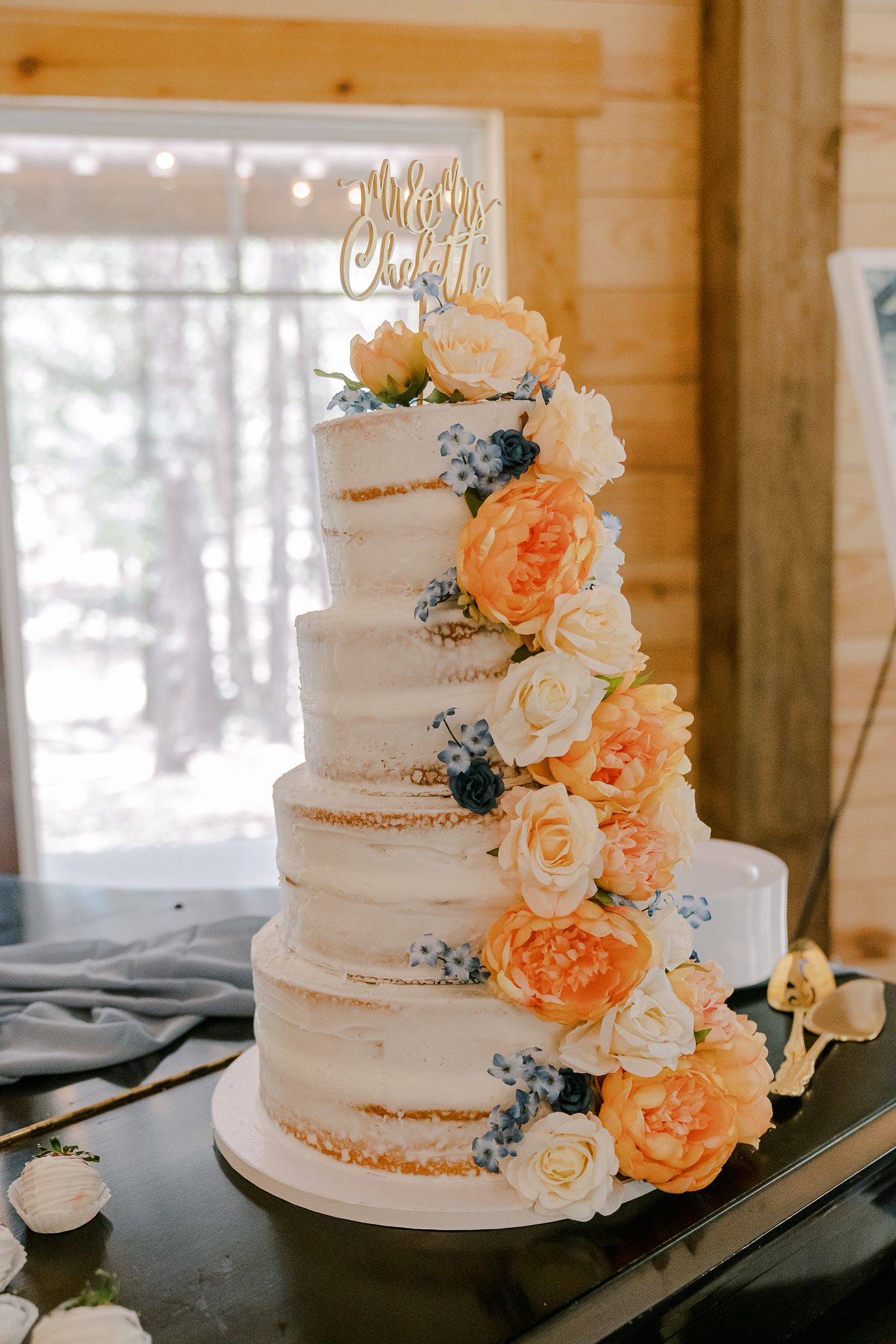 Three views of an elegant white semi-naked wedding cake decorated with peach roses and blue accents at a rustic venue.