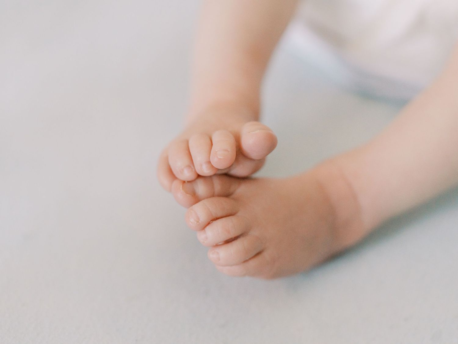 Close-up view of tiny baby feet and toes against a white background.