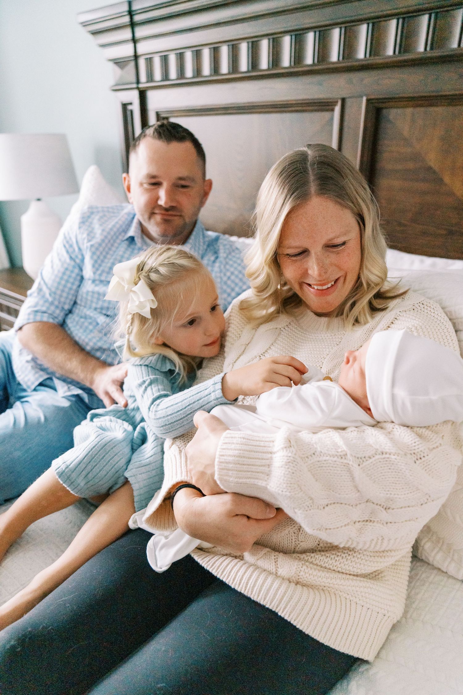Parents share intimate moment with newborn baby while relaxing on couch.