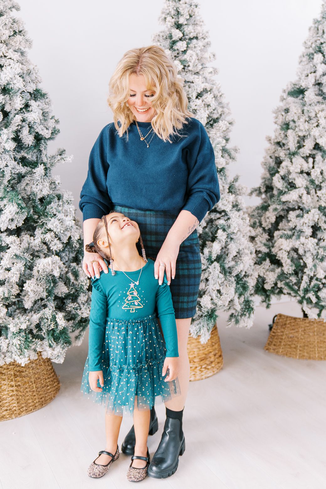 A heartwarming holiday moment captured against snow-covered Christmas trees and woven baskets.