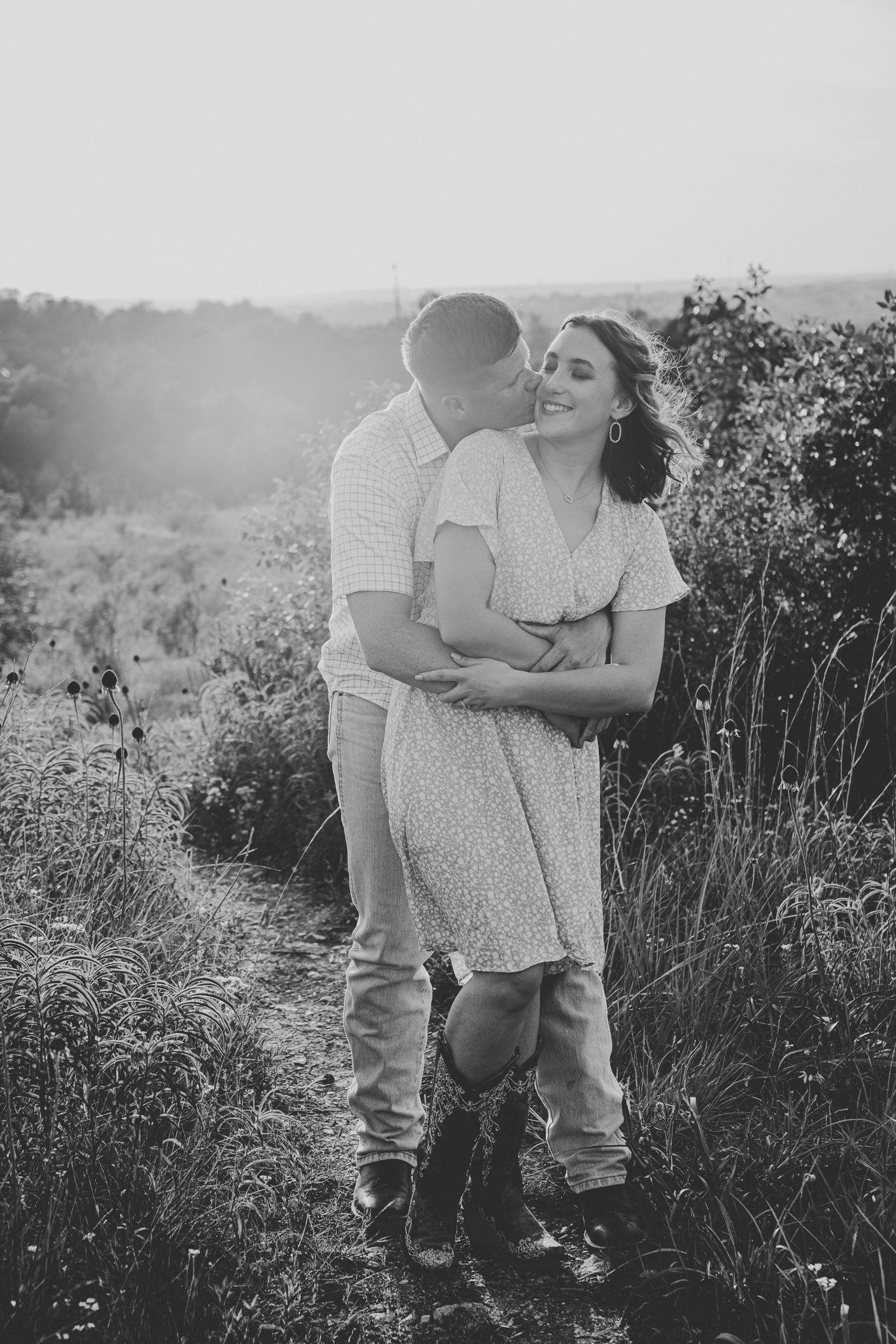 A romantic black and white photo series of a couple sharing tender moments in a wildflower field.