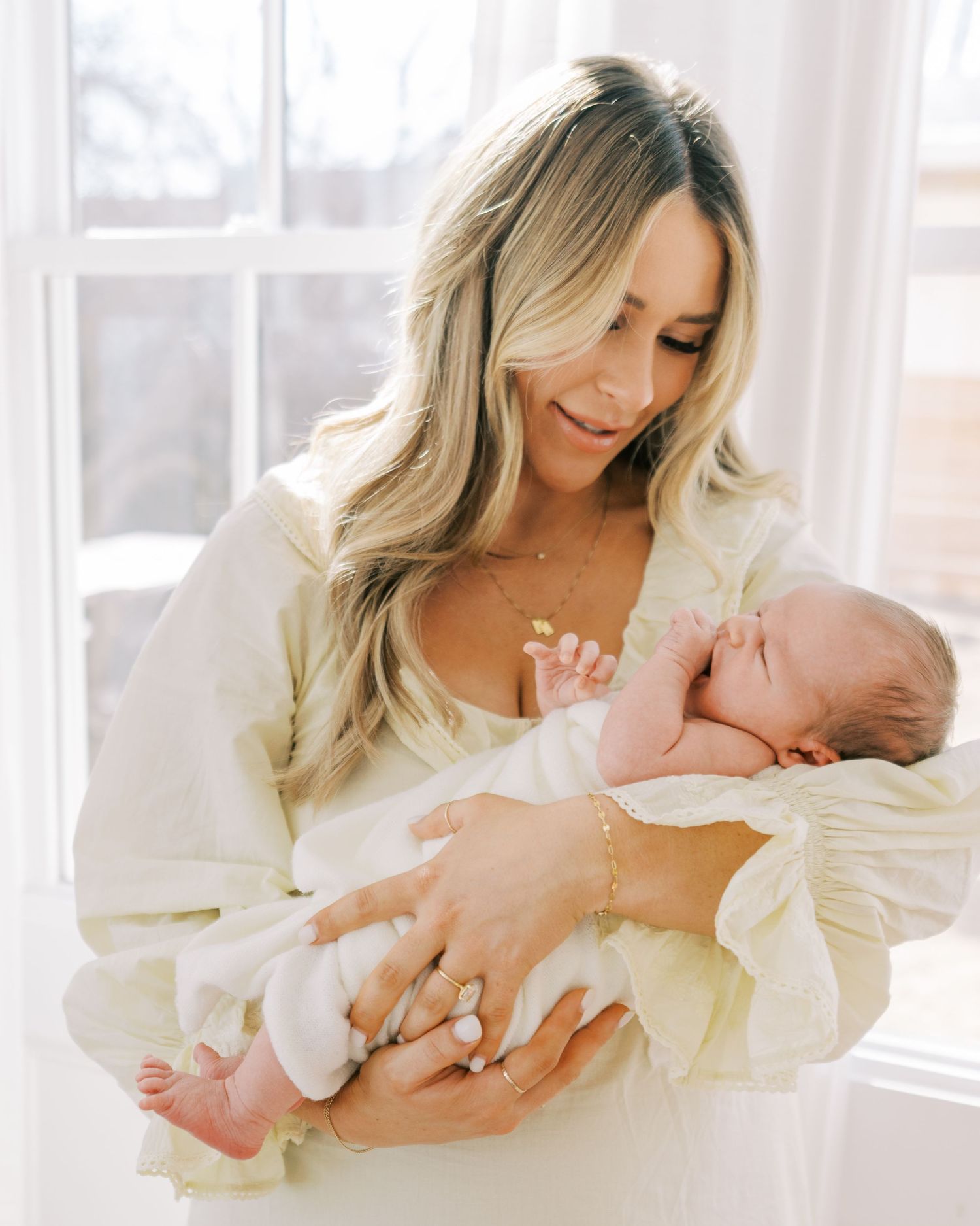A tender moment captured in soft light as a parent cradles and bonds with their newborn baby in white.