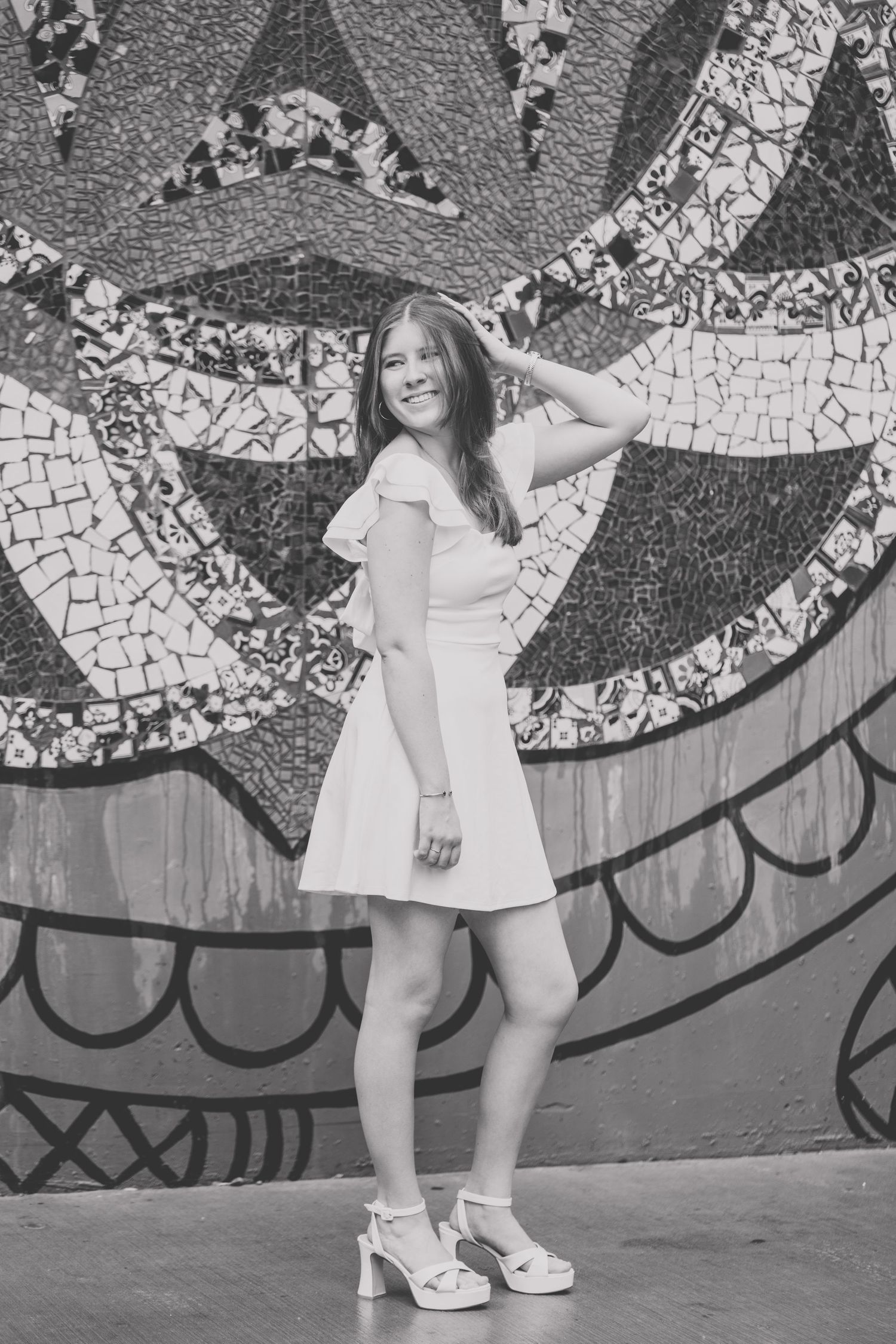 A series of black and white photos showing someone in a white dress posing against a decorative mosaic wall.