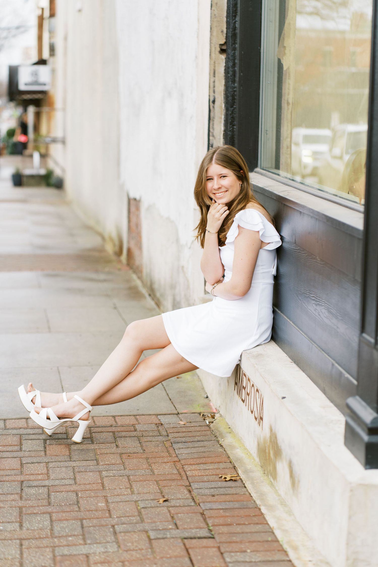 A series of four lifestyle portraits taken on a brick sidewalk against a storefront window.