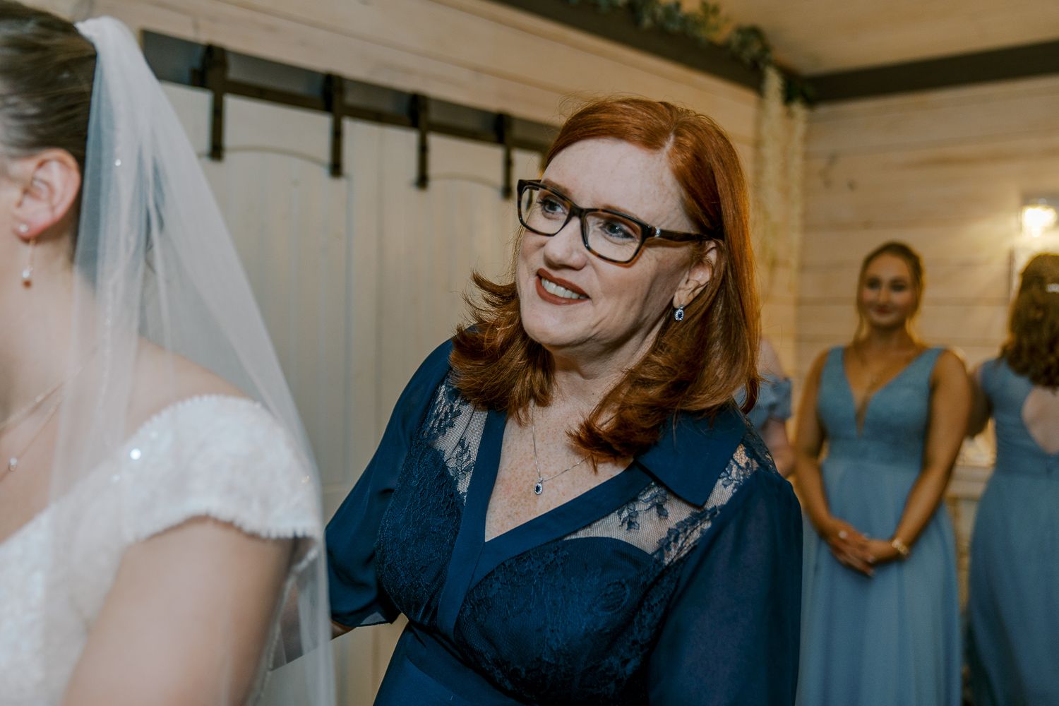 Wedding party members in navy and blue dresses share a joyful moment during preparations.