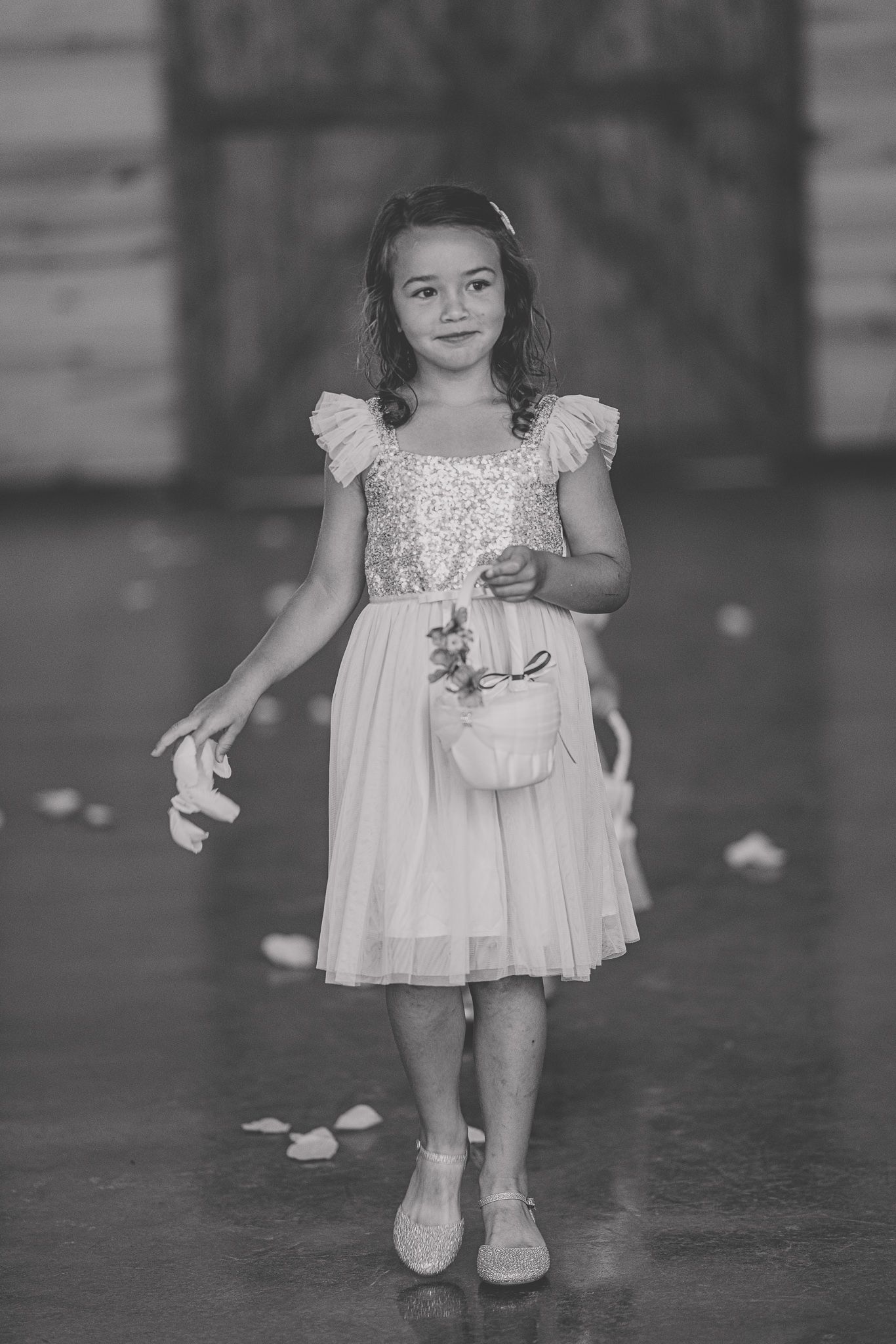 A series of black and white photos showing small feet in a white dress against a dark floor with scattered petals.