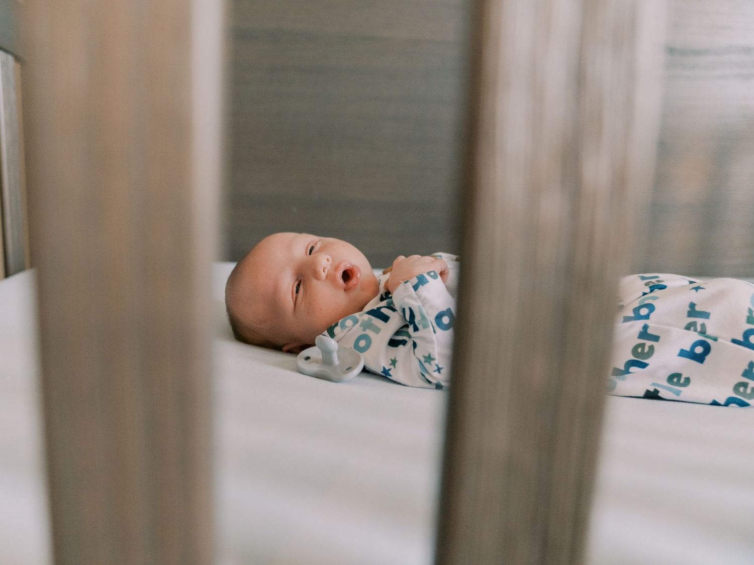 Close-up view of sleeping newborn baby with peaceful expression against white bedding.