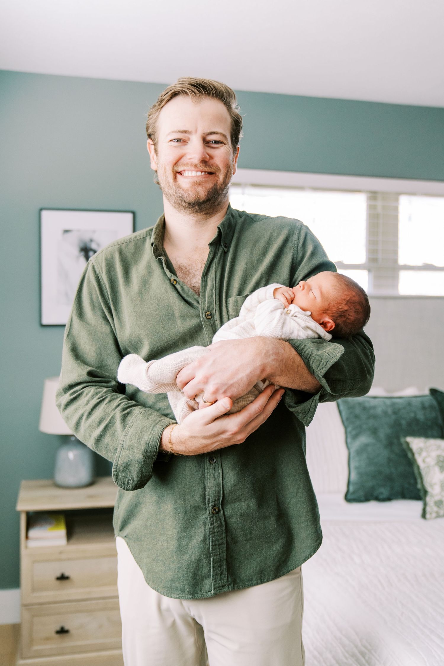 A person in a green shirt holding and bonding with a newborn baby in a bright room.