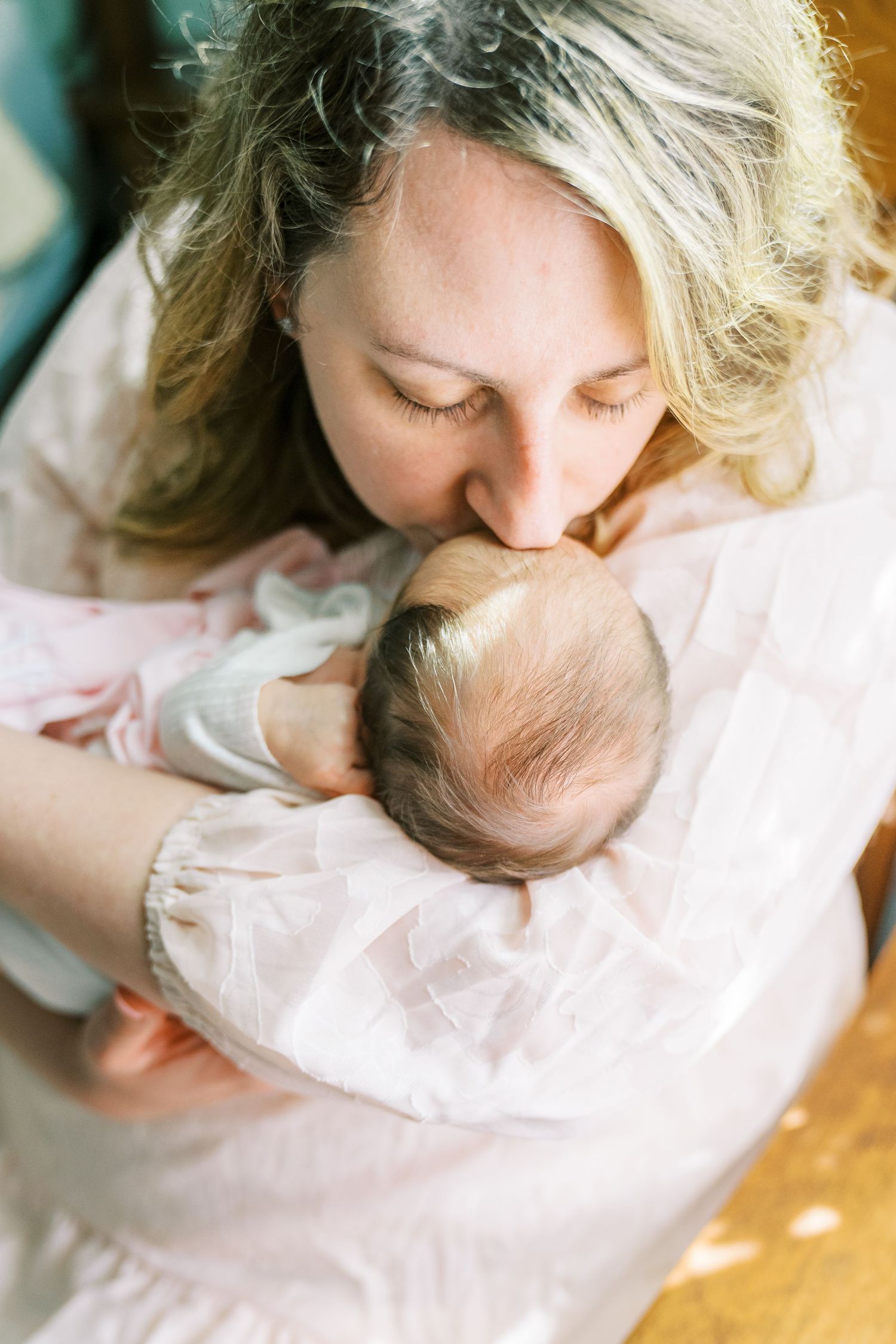 Tender moment between parent and newborn captured in soft natural lighting.