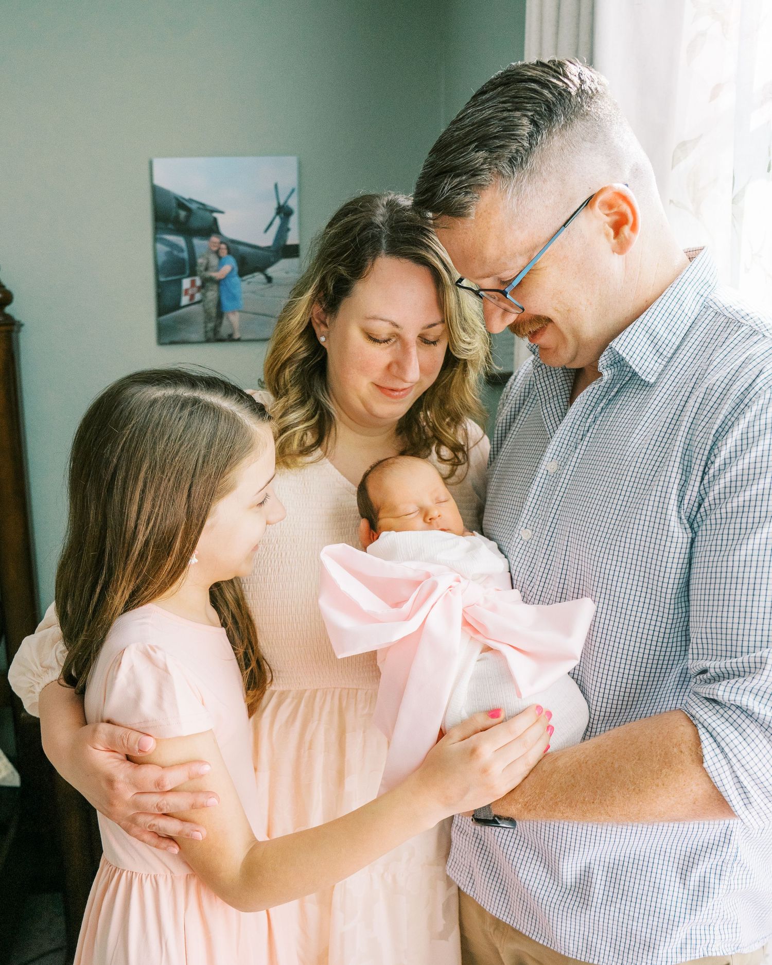 Family sharing tender moments together in a sunlit room with soft pink and gray tones.