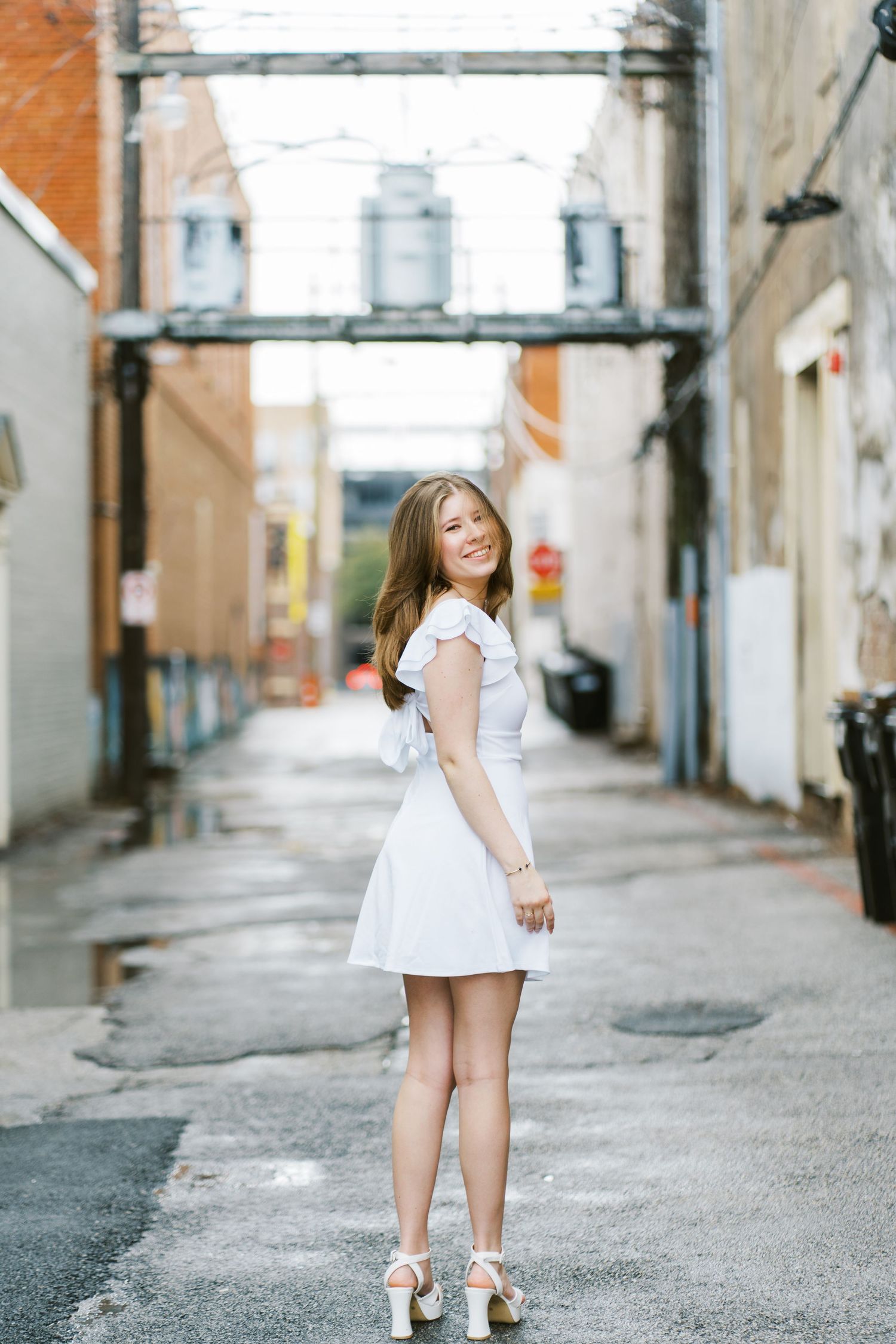 A series of five connected photos showing someone in a white dress walking down an urban alleyway.