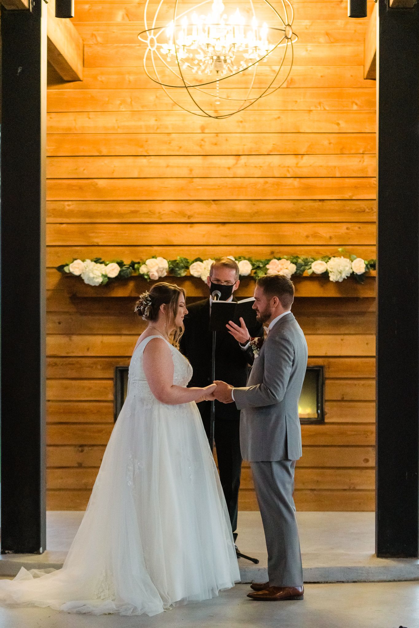 A wedding ceremony takes place in a rustic wooden barn venue with warm lighting and elegant decor.