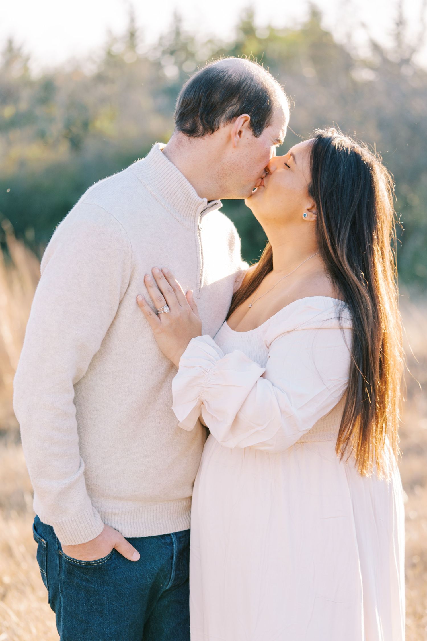 Romantic moment between couple in matching cream sweaters during outdoor photoshoot.