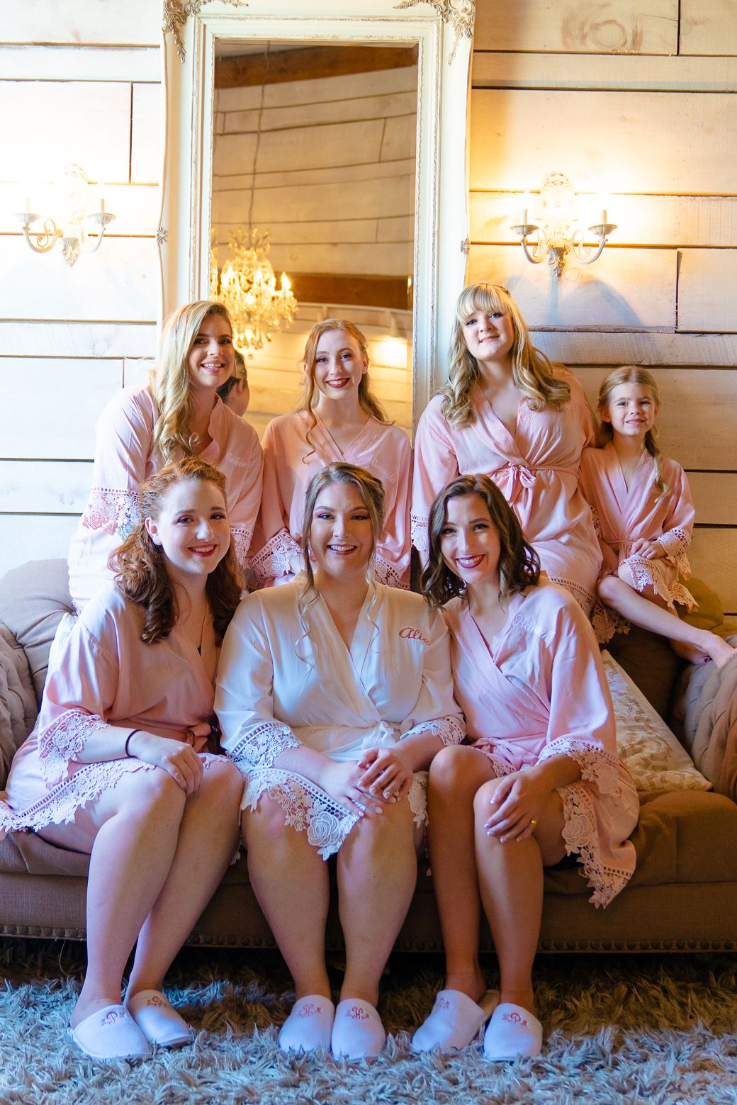 A group wearing matching pink robes poses together on a carpeted floor in front of a couch.