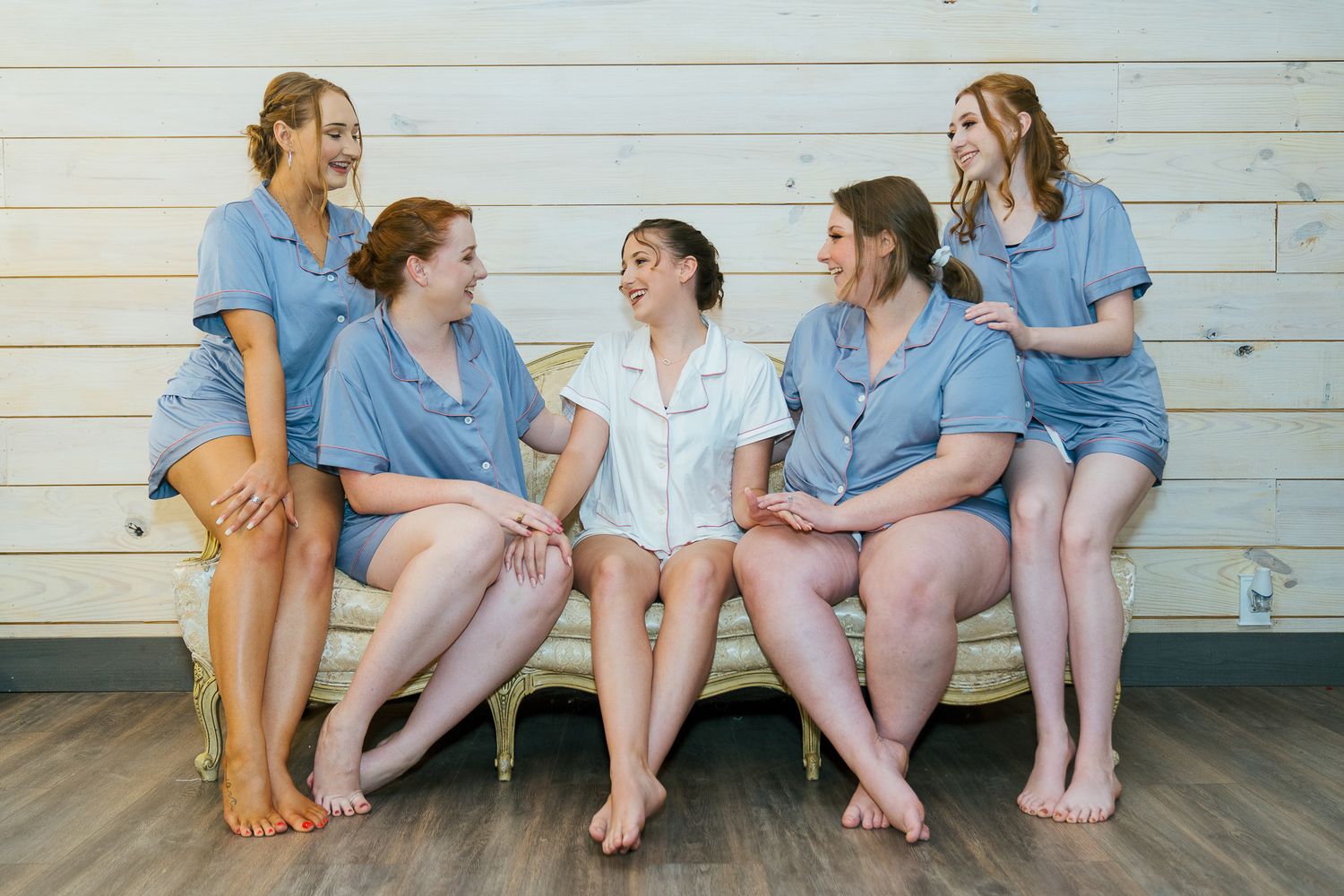 Group of friends in matching blue outfits sitting casually on a white wooden porch.